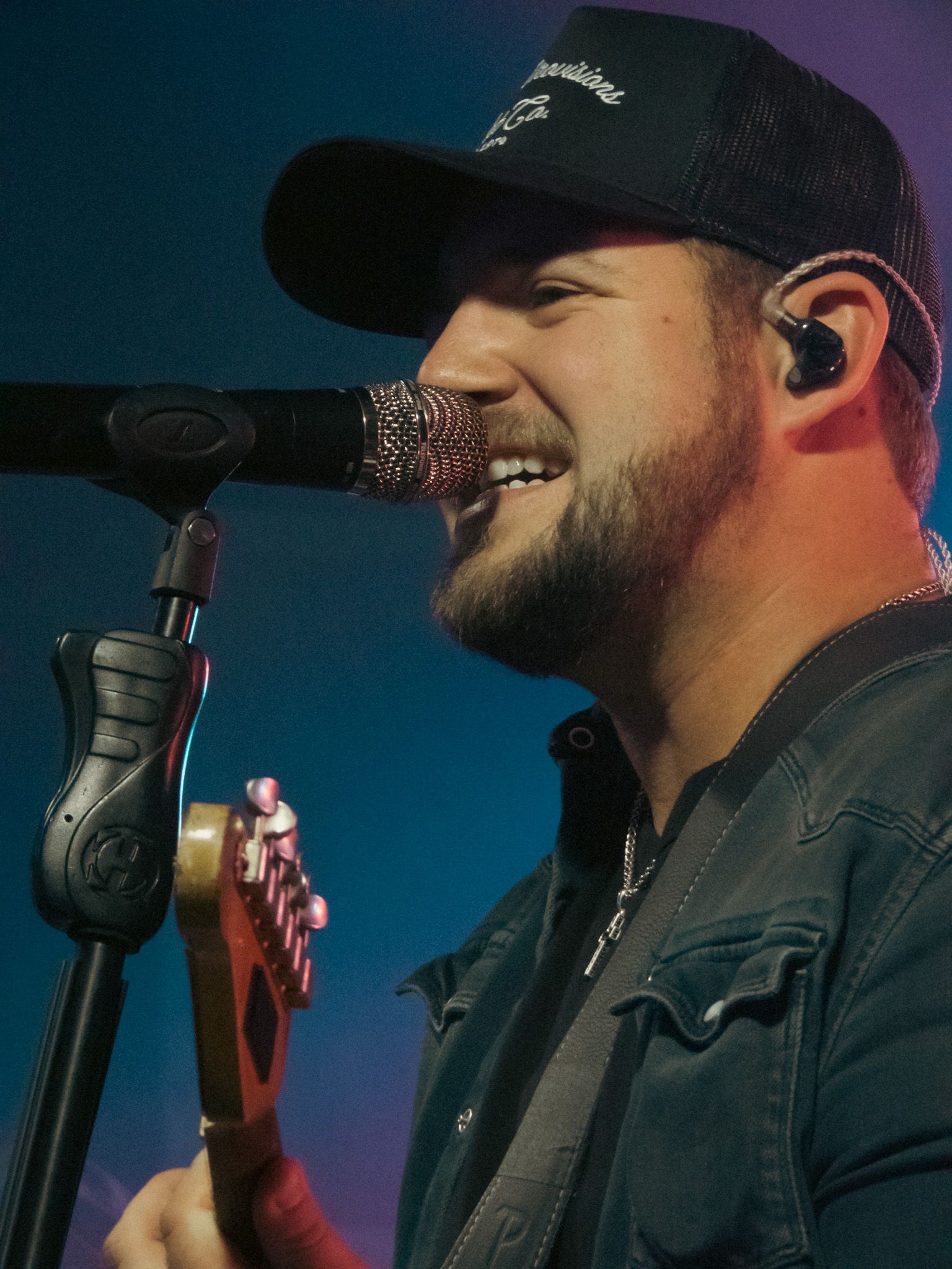 A man singing into a microphone while holding a guitar