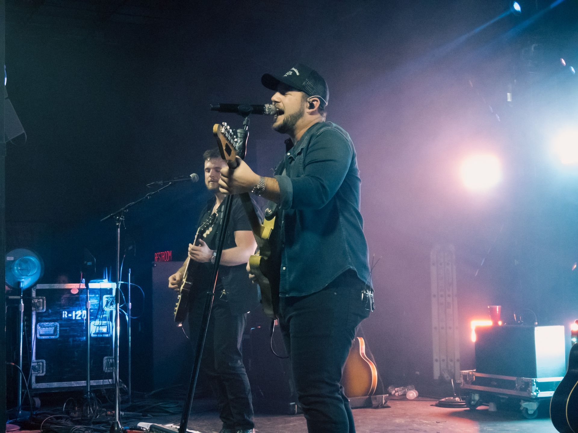 A man is singing into a microphone while playing a guitar on stage.