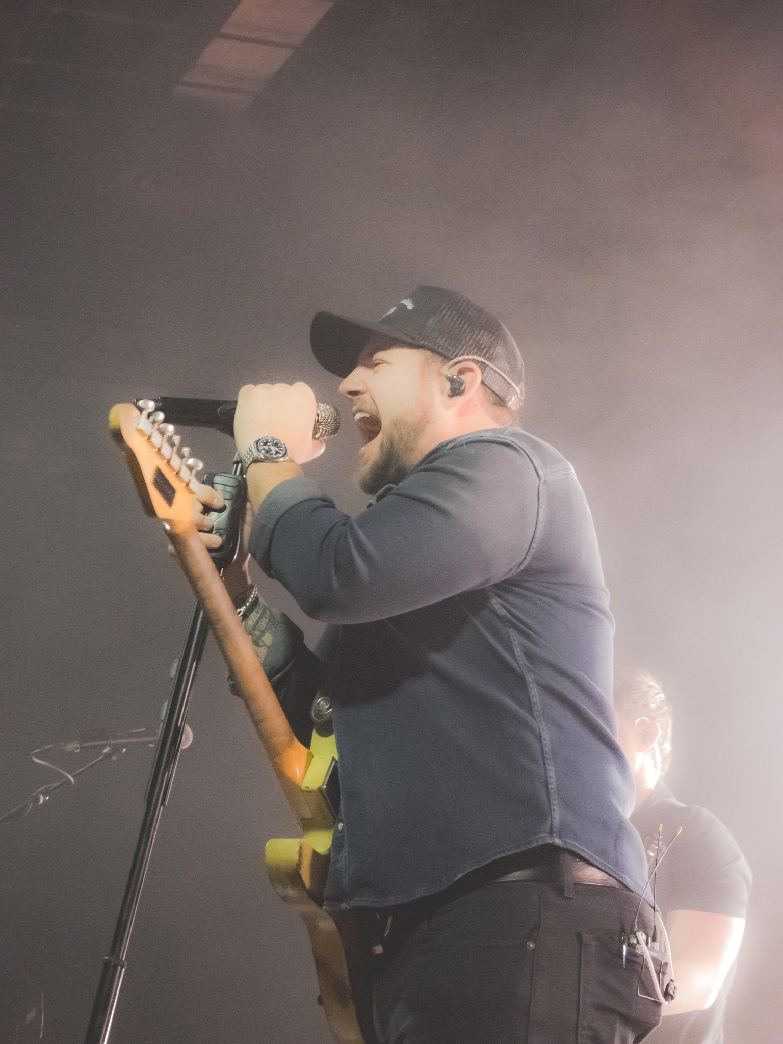 A man singing into a microphone while holding a guitar