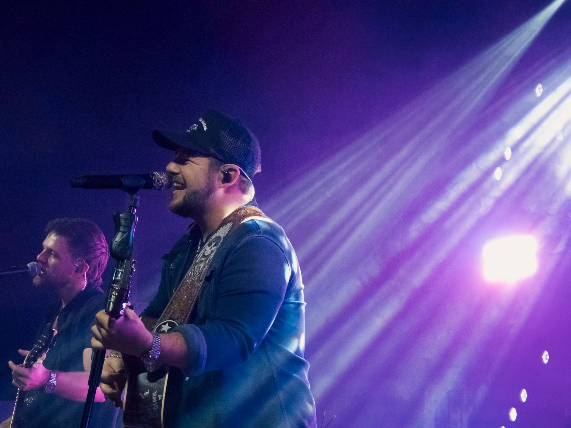 A man is singing into a microphone while playing a guitar on a stage.