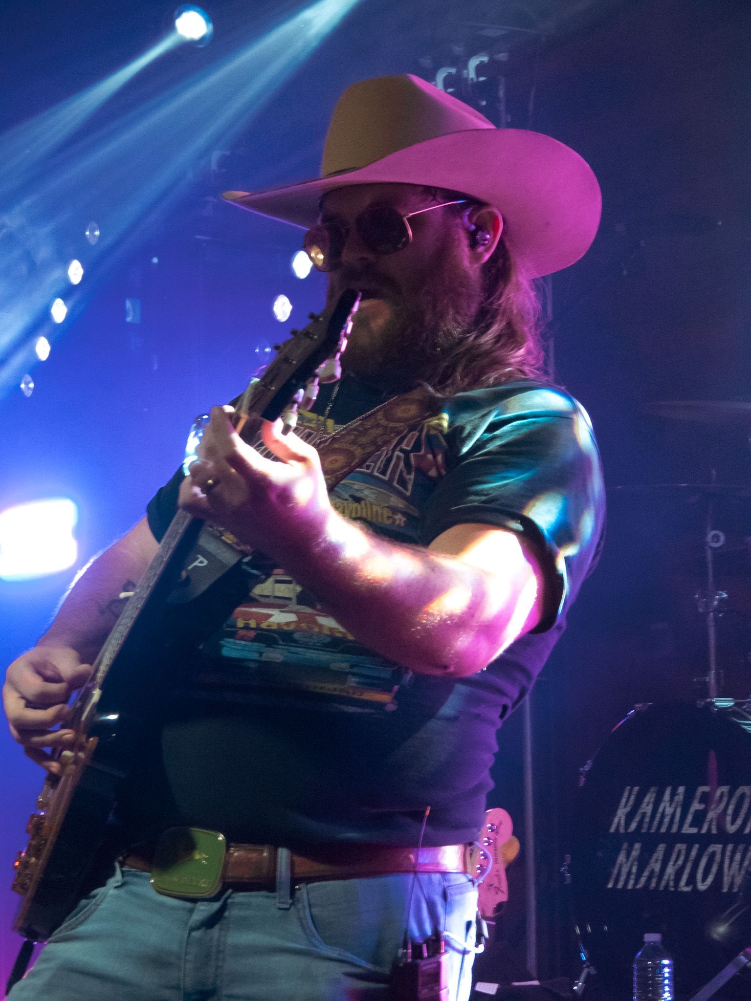 A man in a cowboy hat is playing a guitar on stage