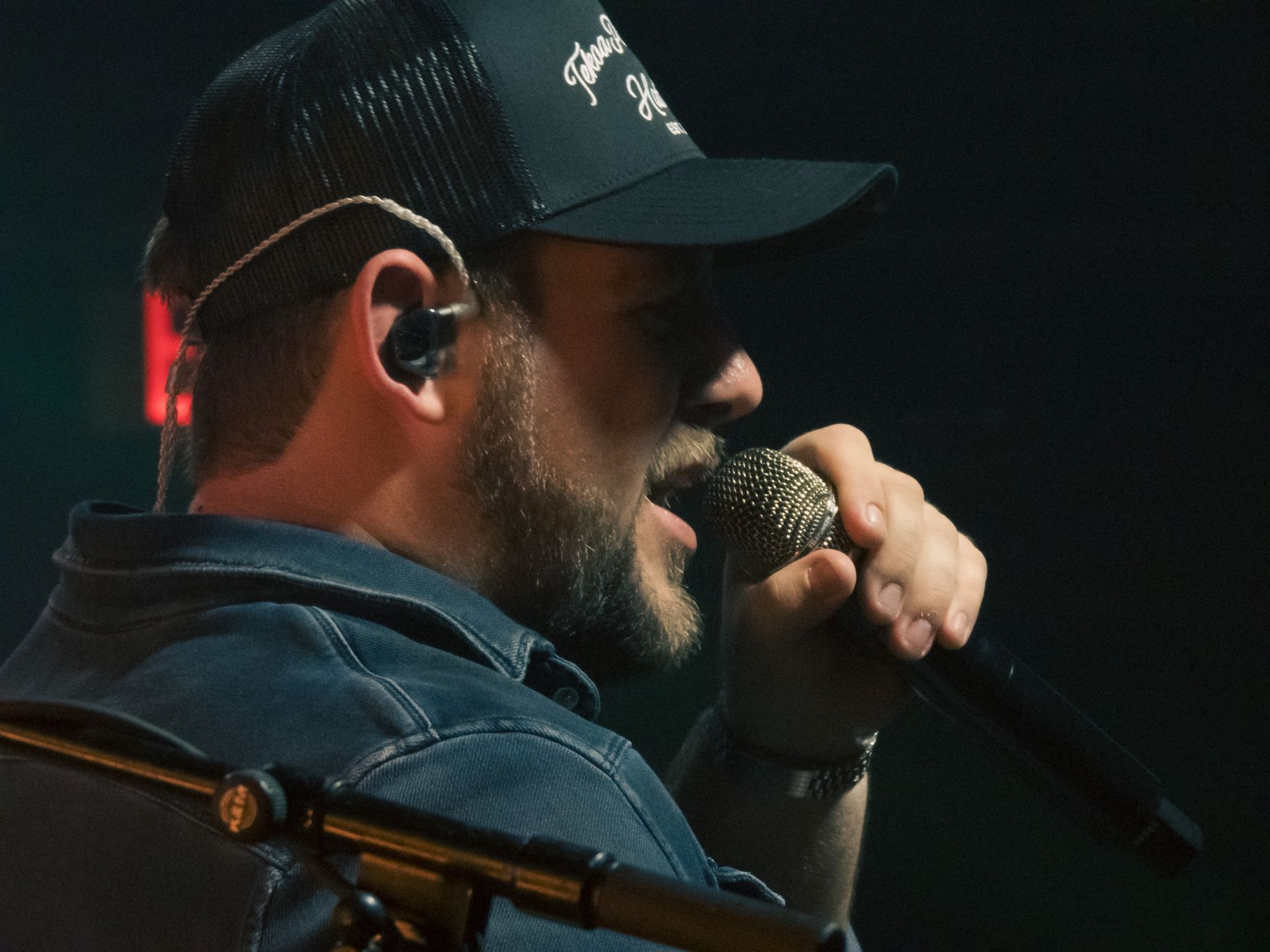 A man wearing a hat is singing into a microphone
