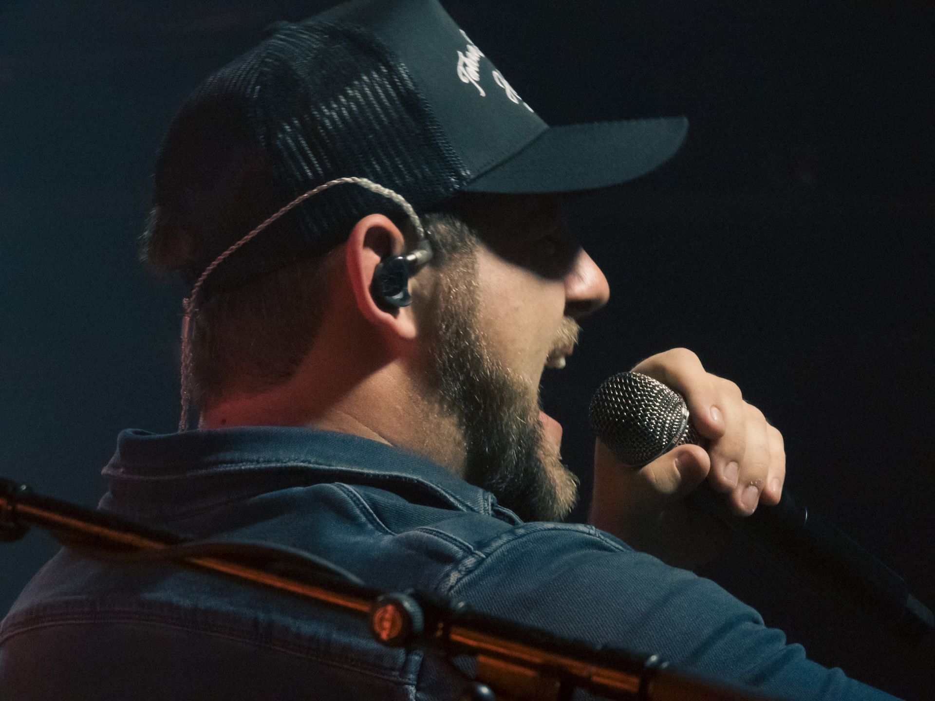 A man wearing a hat is singing into a microphone