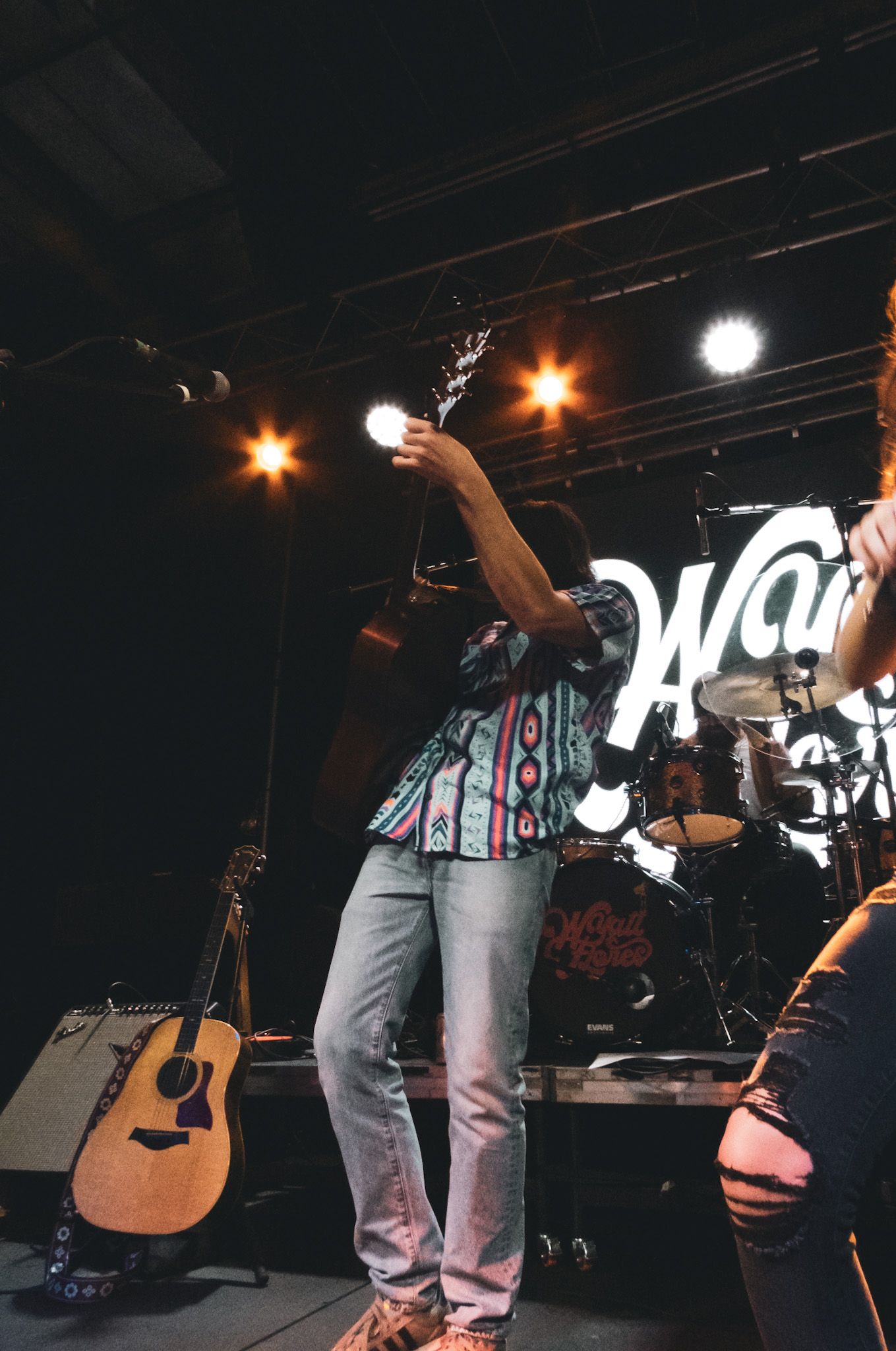A man is singing into a microphone while playing a guitar on stage.
