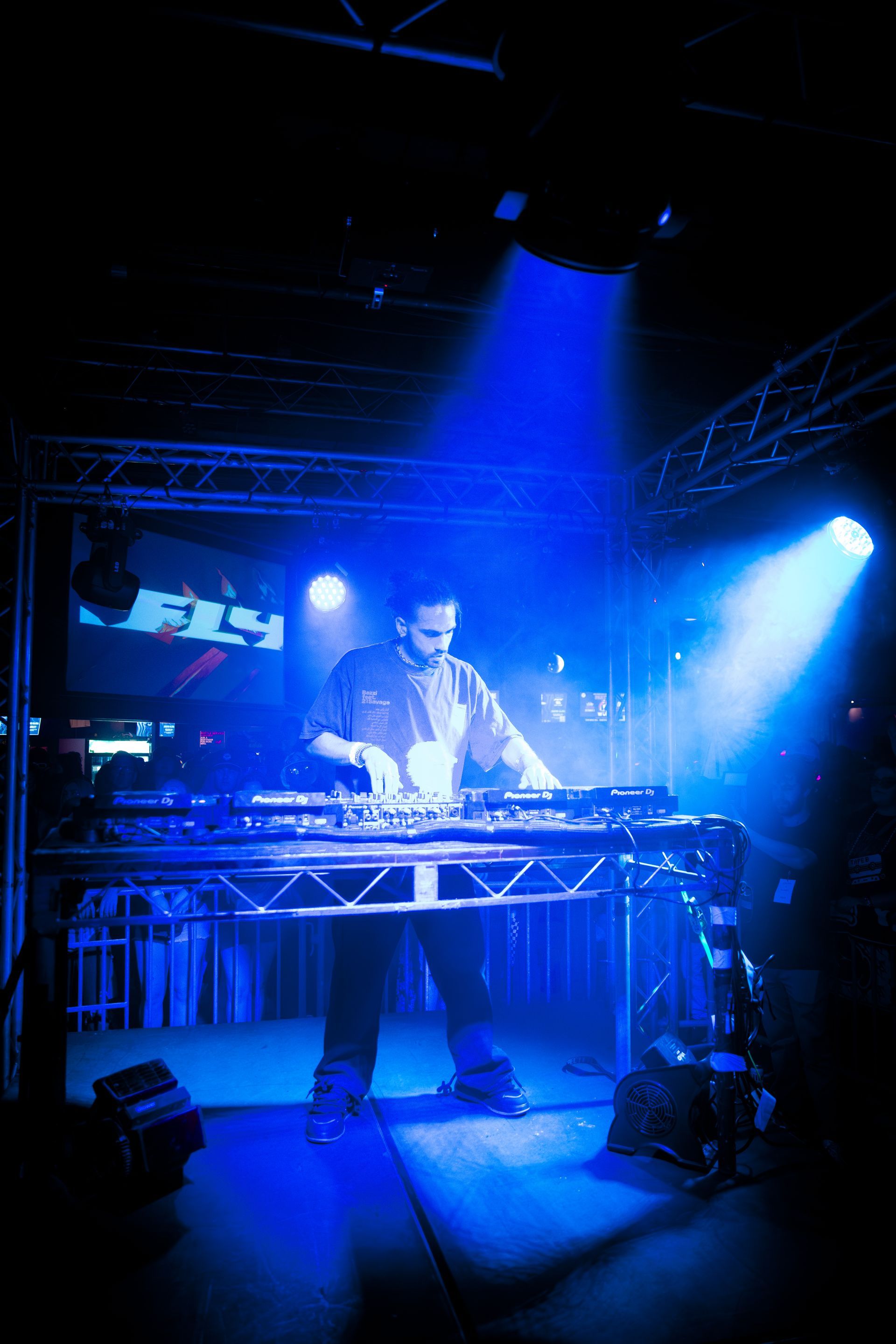A man is playing a dj set in a dark room with blue lights
