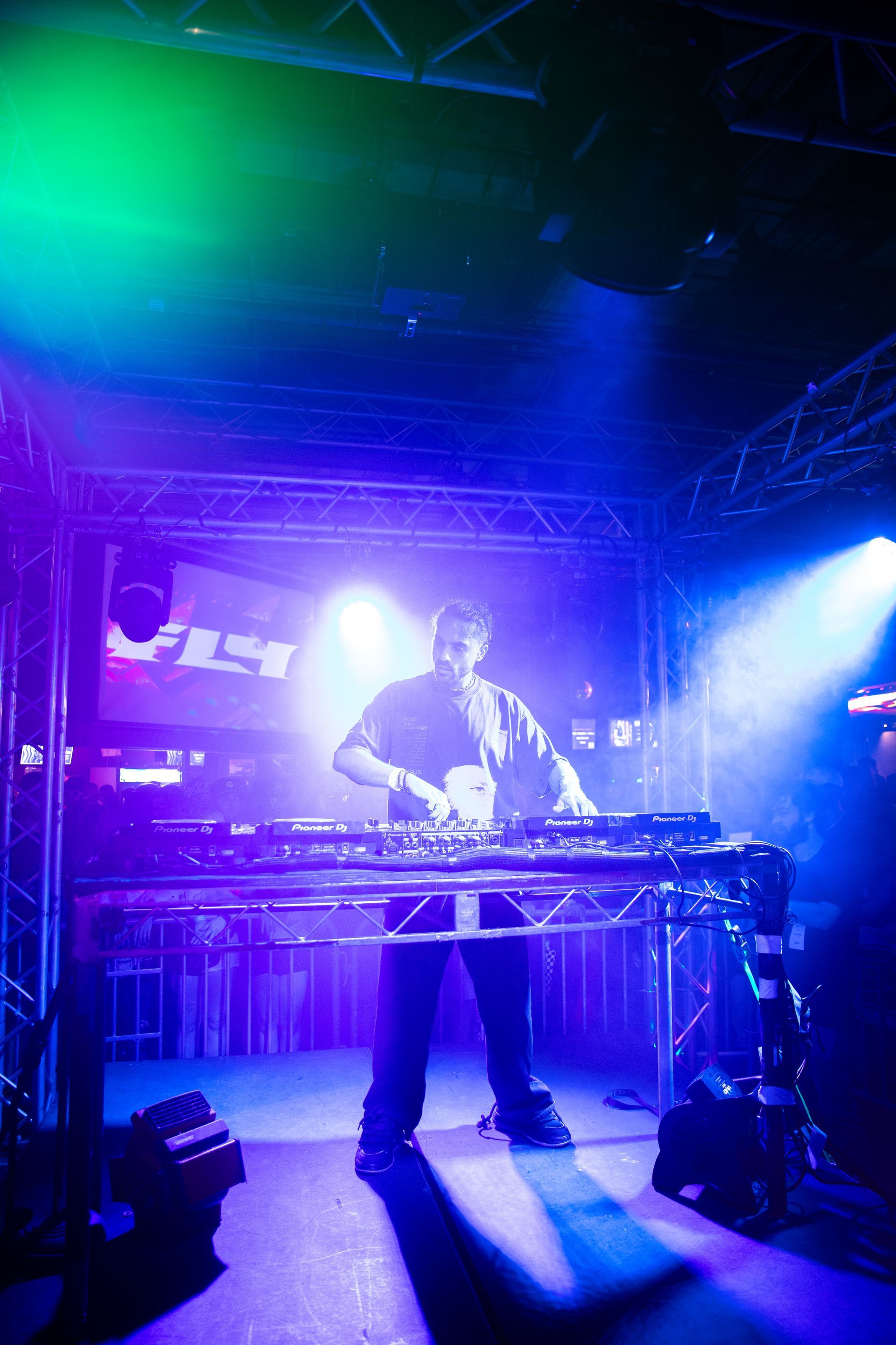 A man is playing a keyboard on a stage in a dark room.