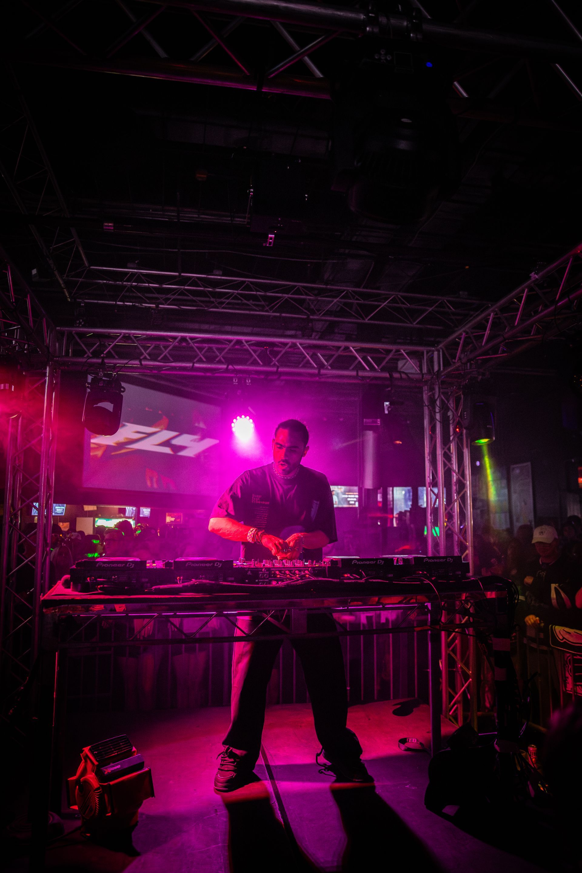 A man is playing a dj set in a dark room with pink lights.