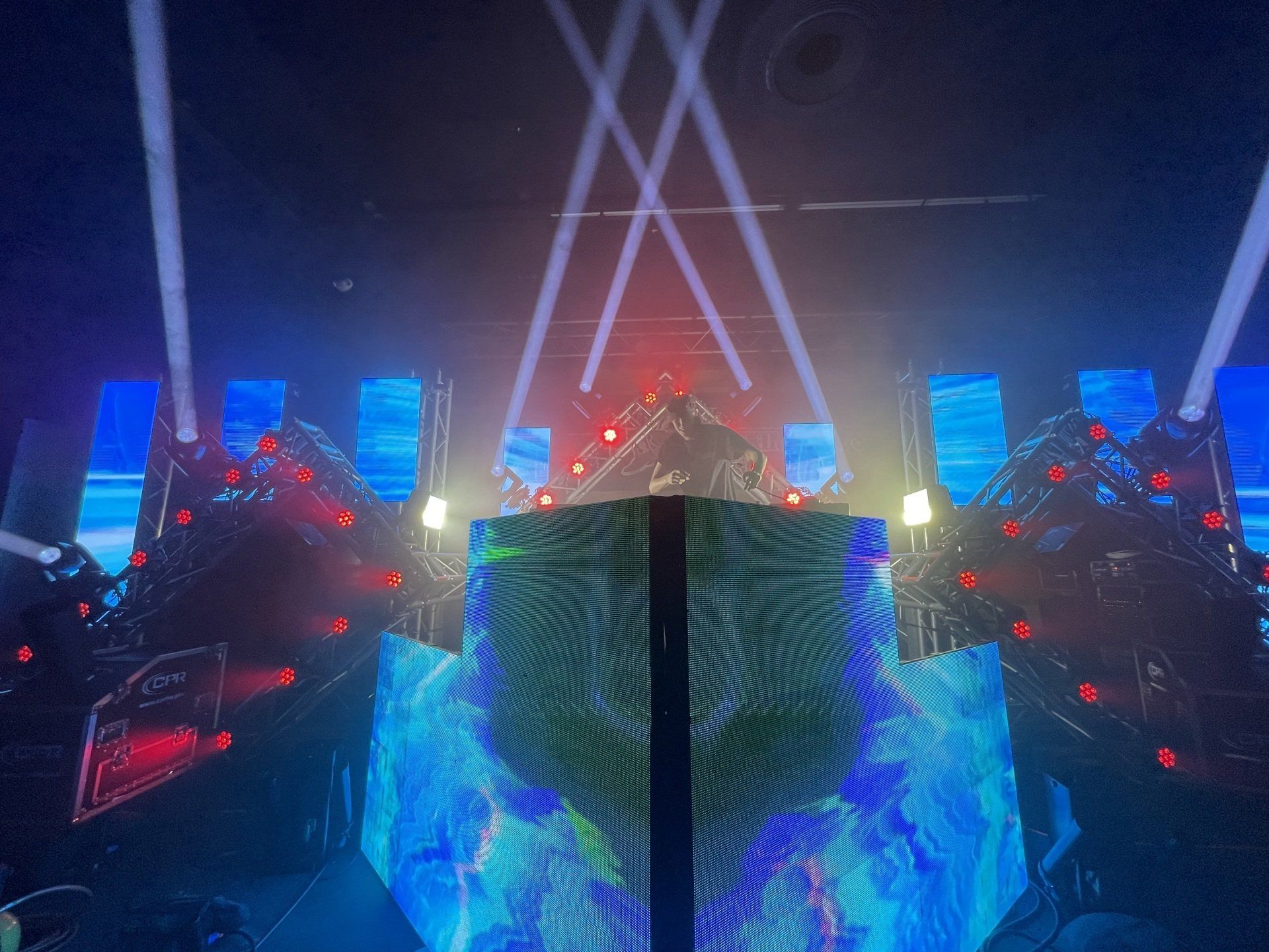 A dj is playing music on a stage with a lot of lights.