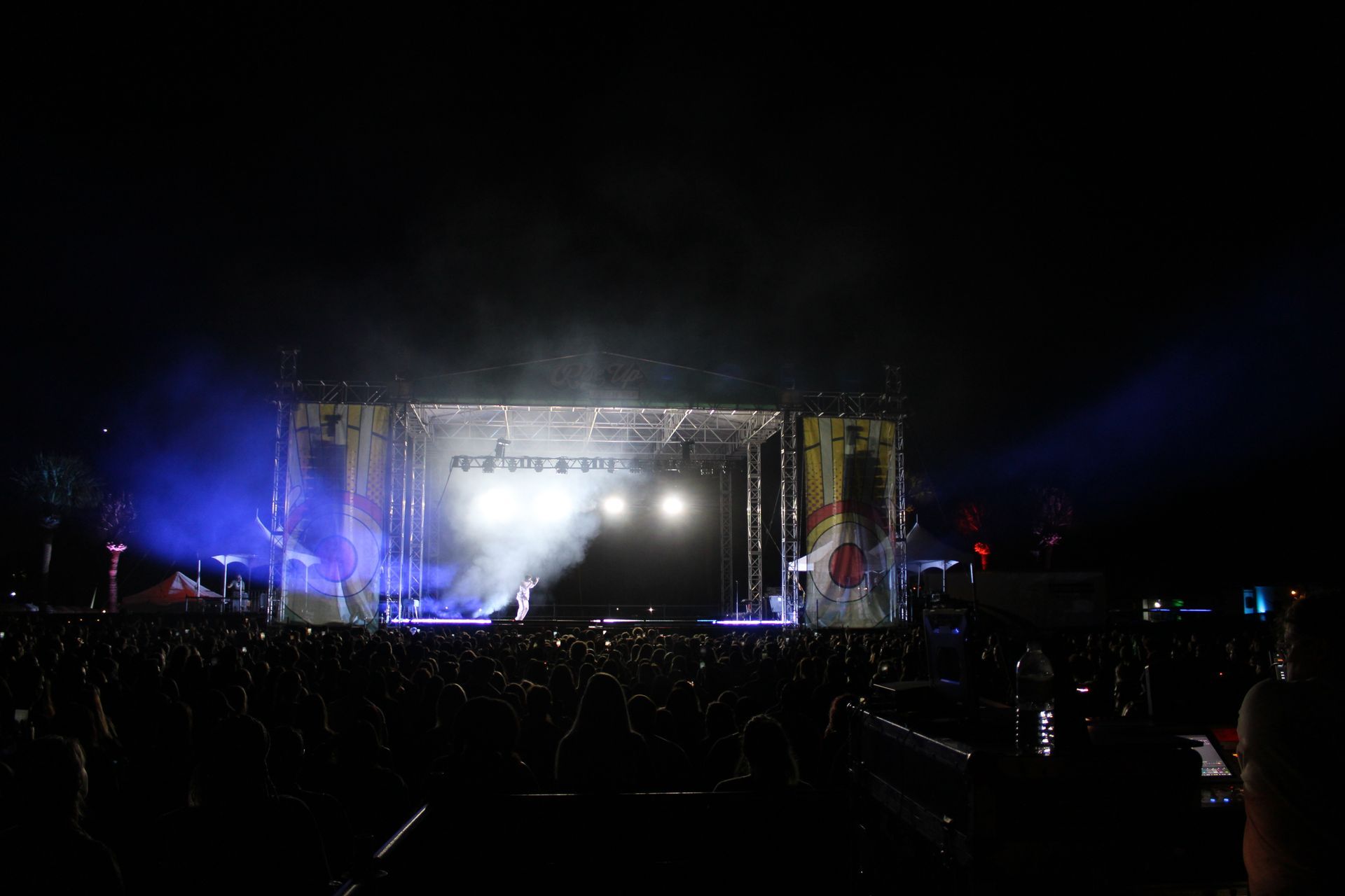 A crowd of people are standing in front of a stage at a concert.
