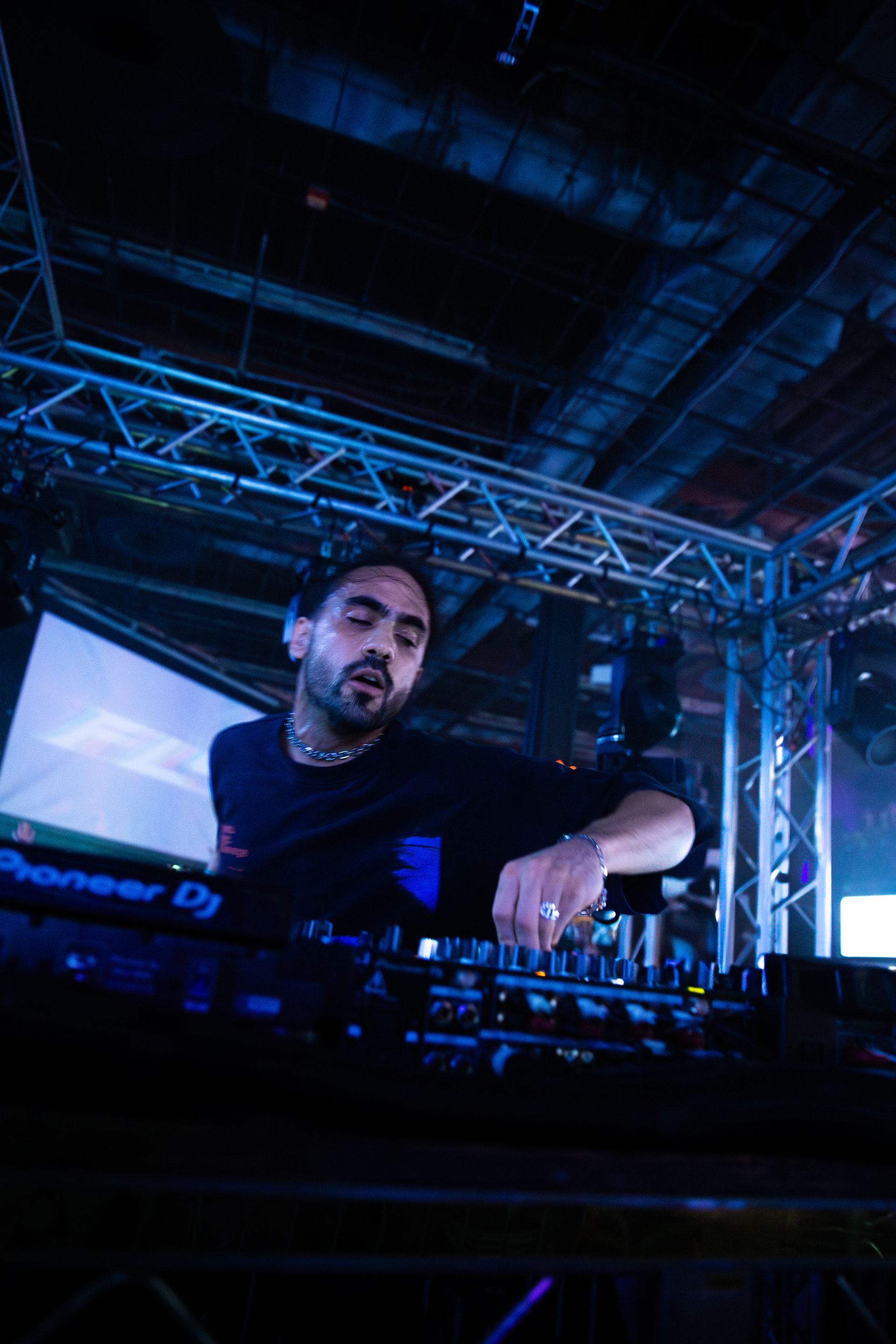 A man is playing a dj set on a stage in a dark room.