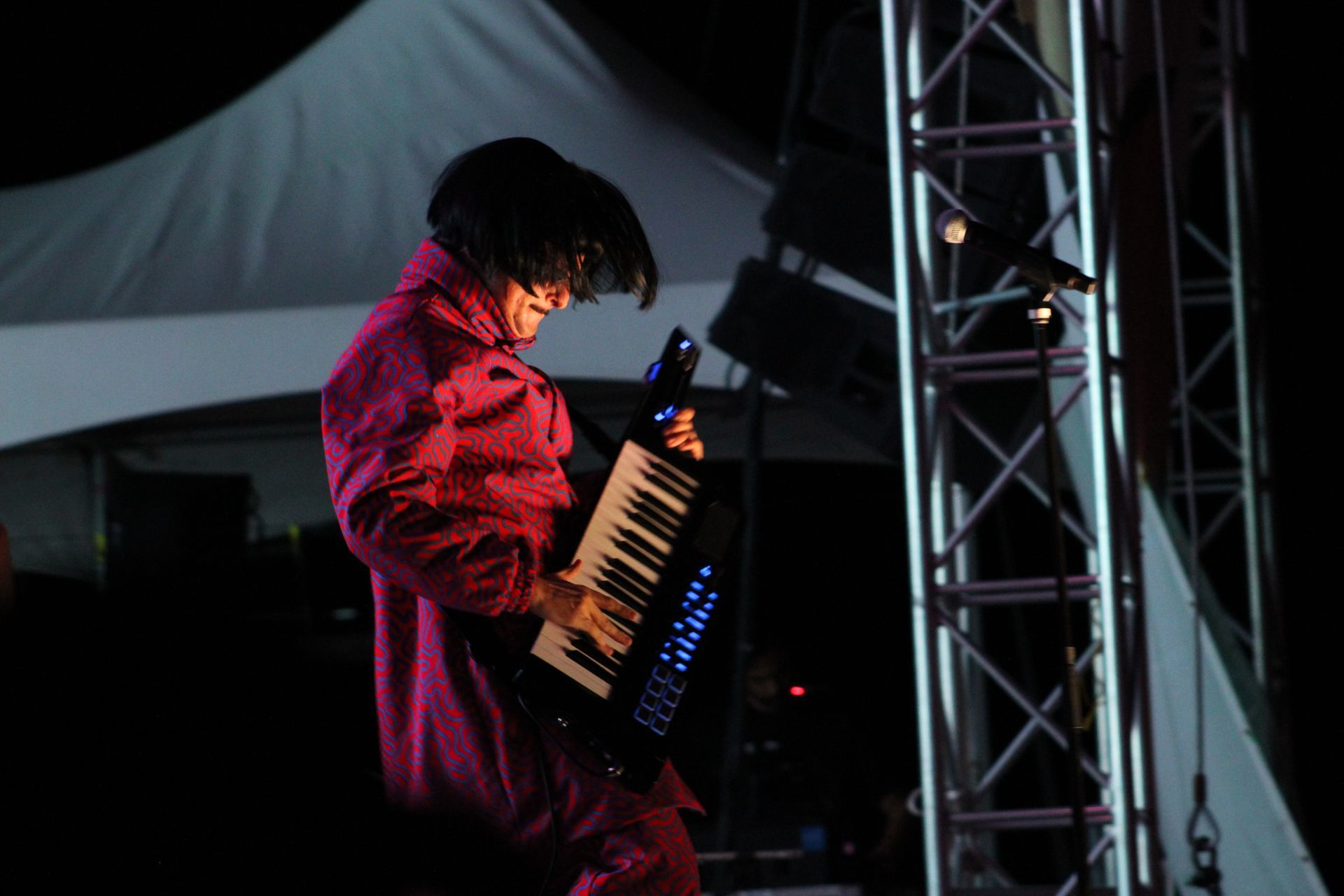 A person in a pink jacket is playing a keyboard on a stage.