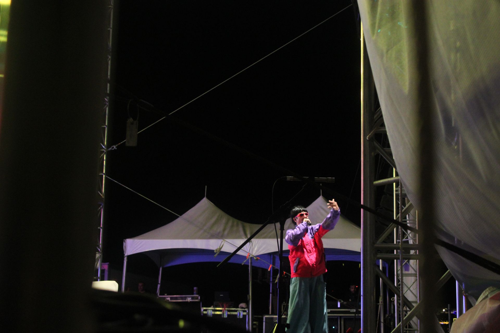 A man is singing into a microphone on a stage at night.