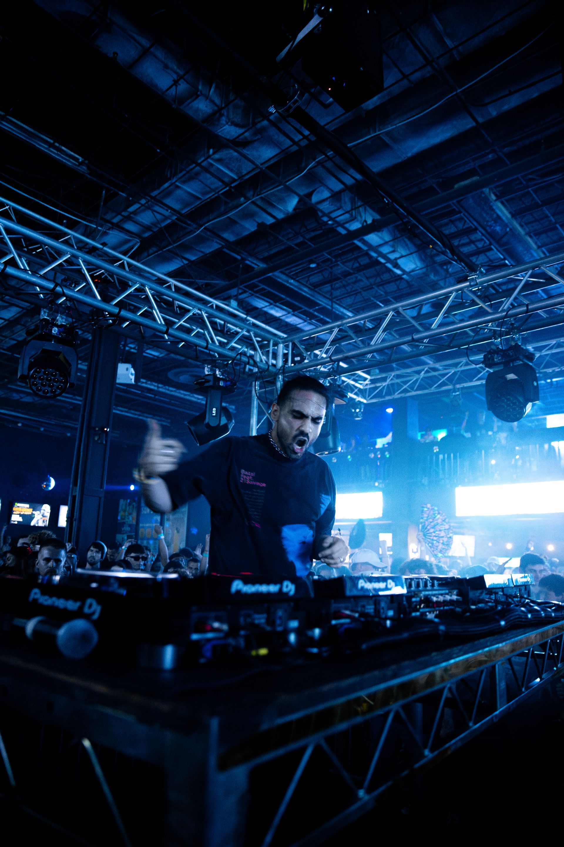 A man is playing a dj set in a dark room.