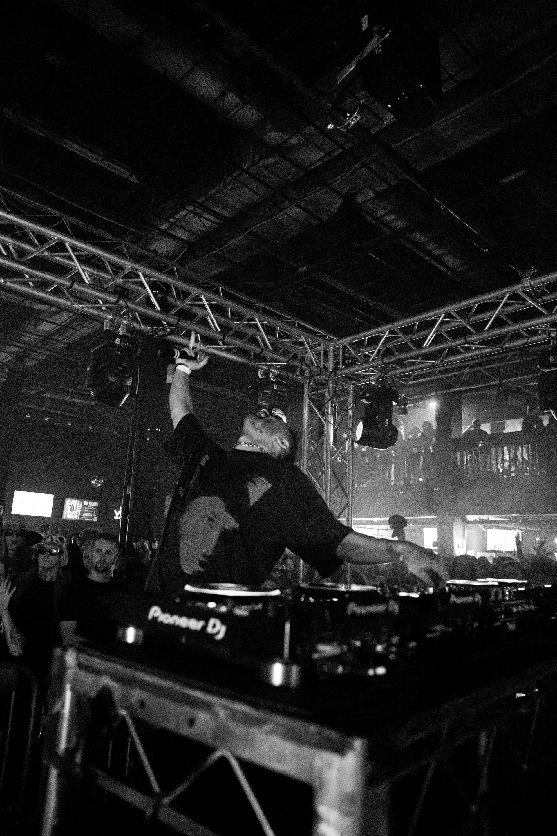 A black and white photo of a dj playing music in a club.