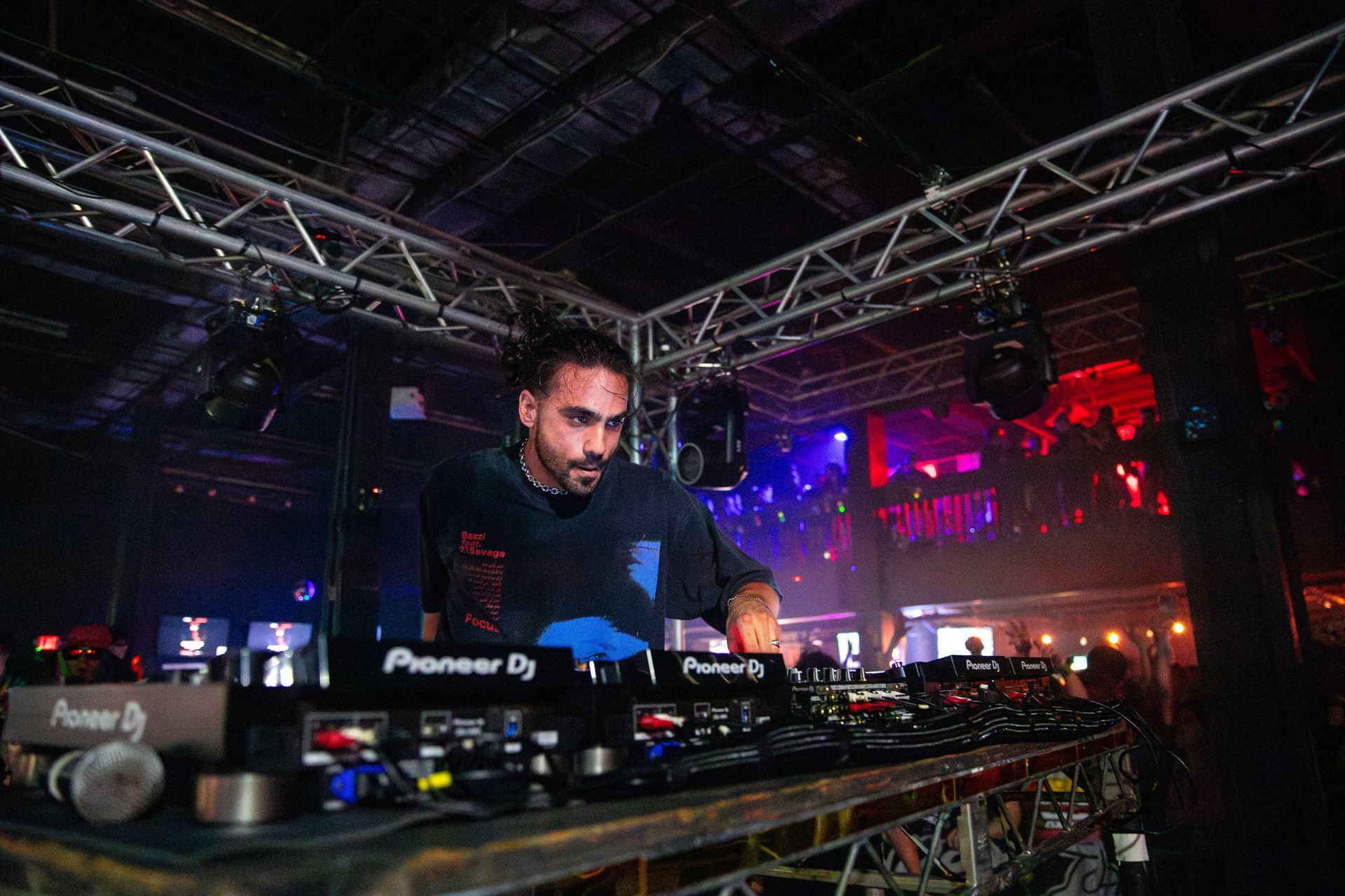 A man is playing a dj set in a dark room.