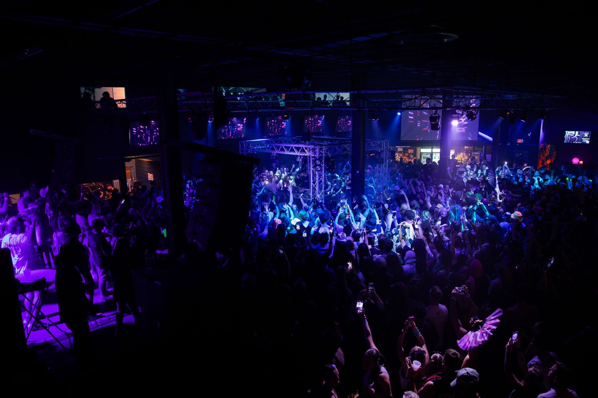 A crowd of people are dancing in a dark room at a concert.