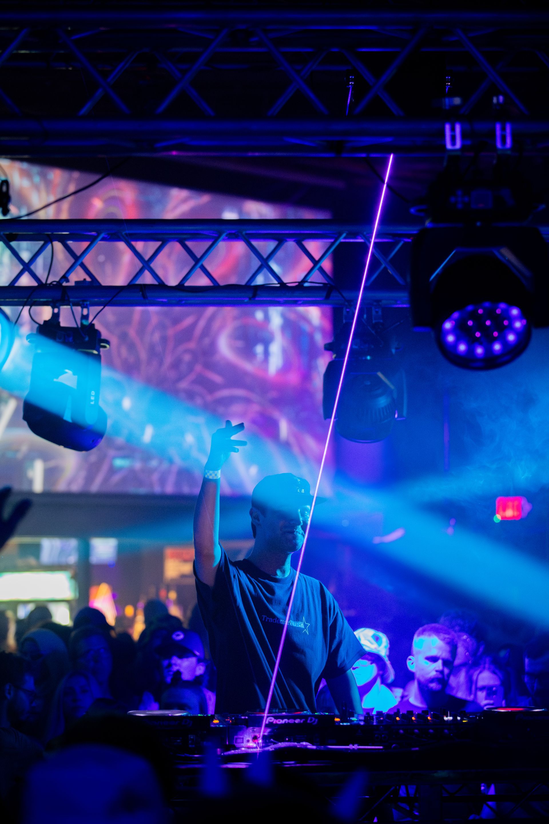 A dj is playing music in front of a crowd at a club.