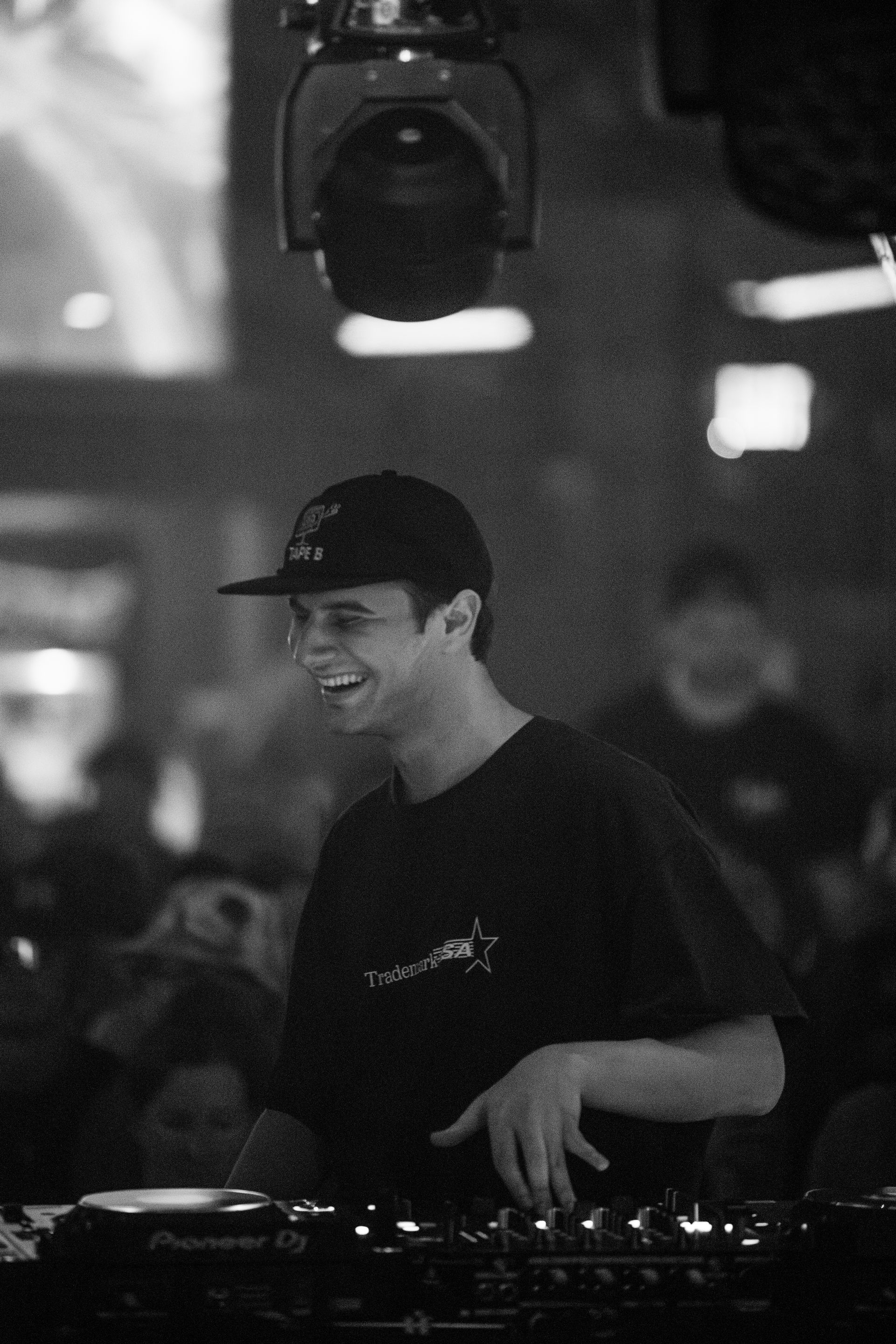 A man in a hat is playing a dj set in a black and white photo.