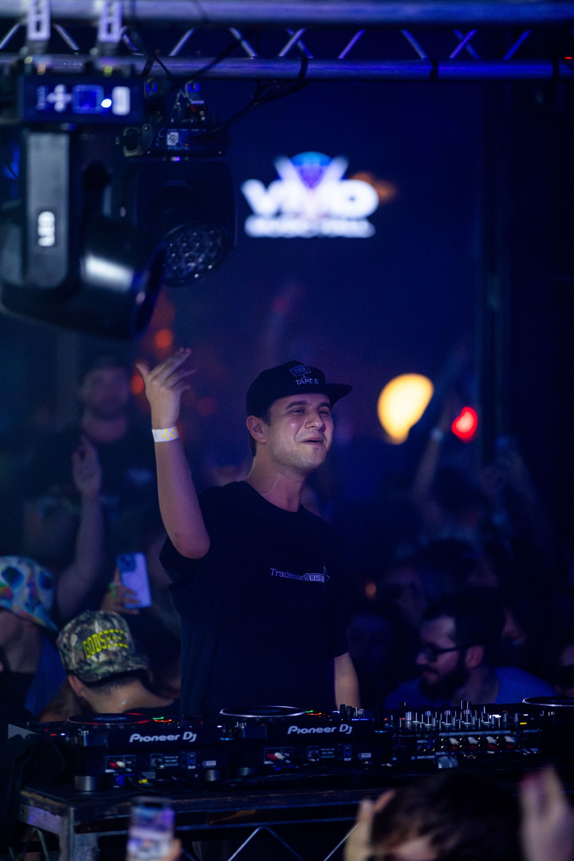 A dj is standing in front of a crowd at a concert.