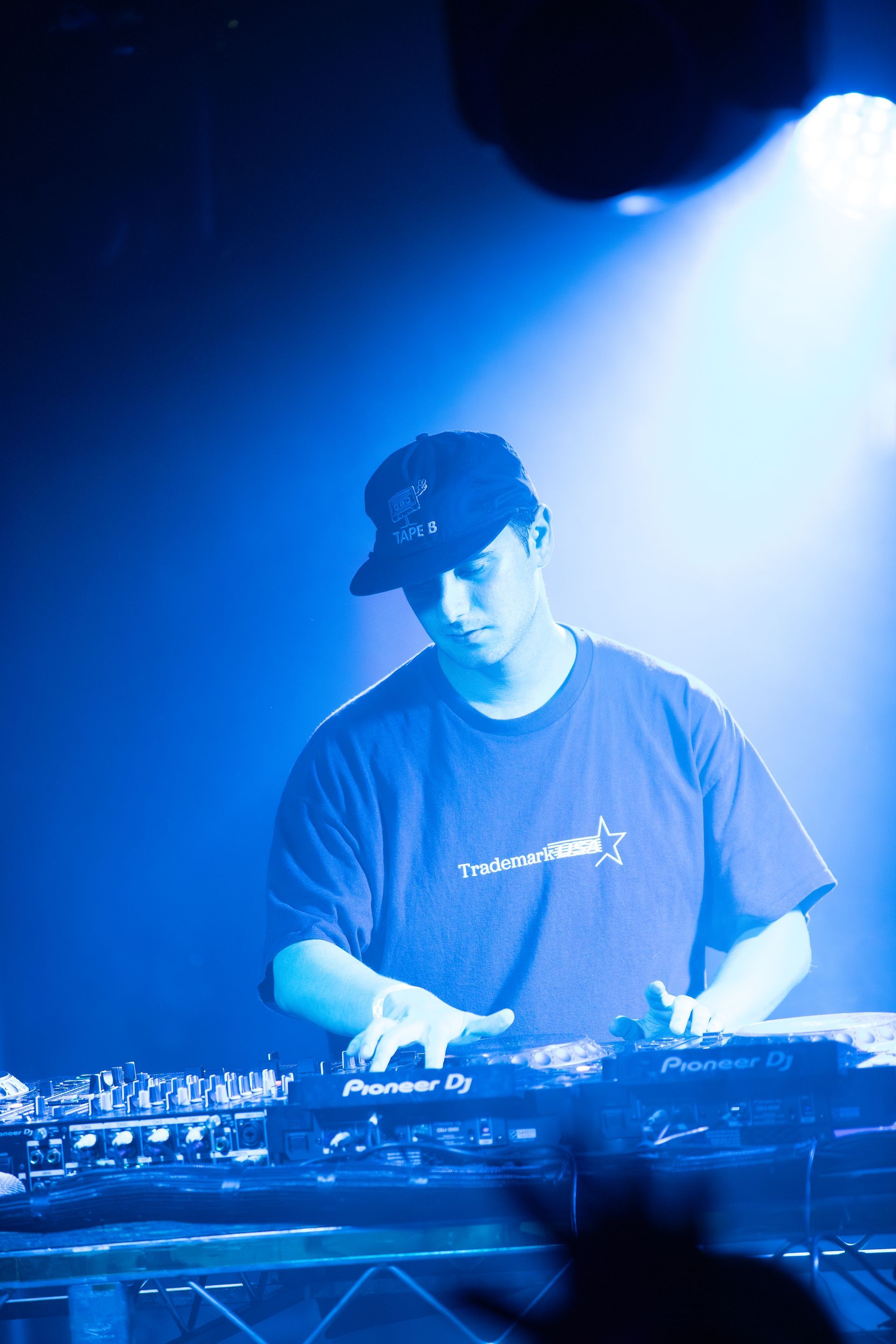 A man in a hat is playing a keyboard in a dark room.