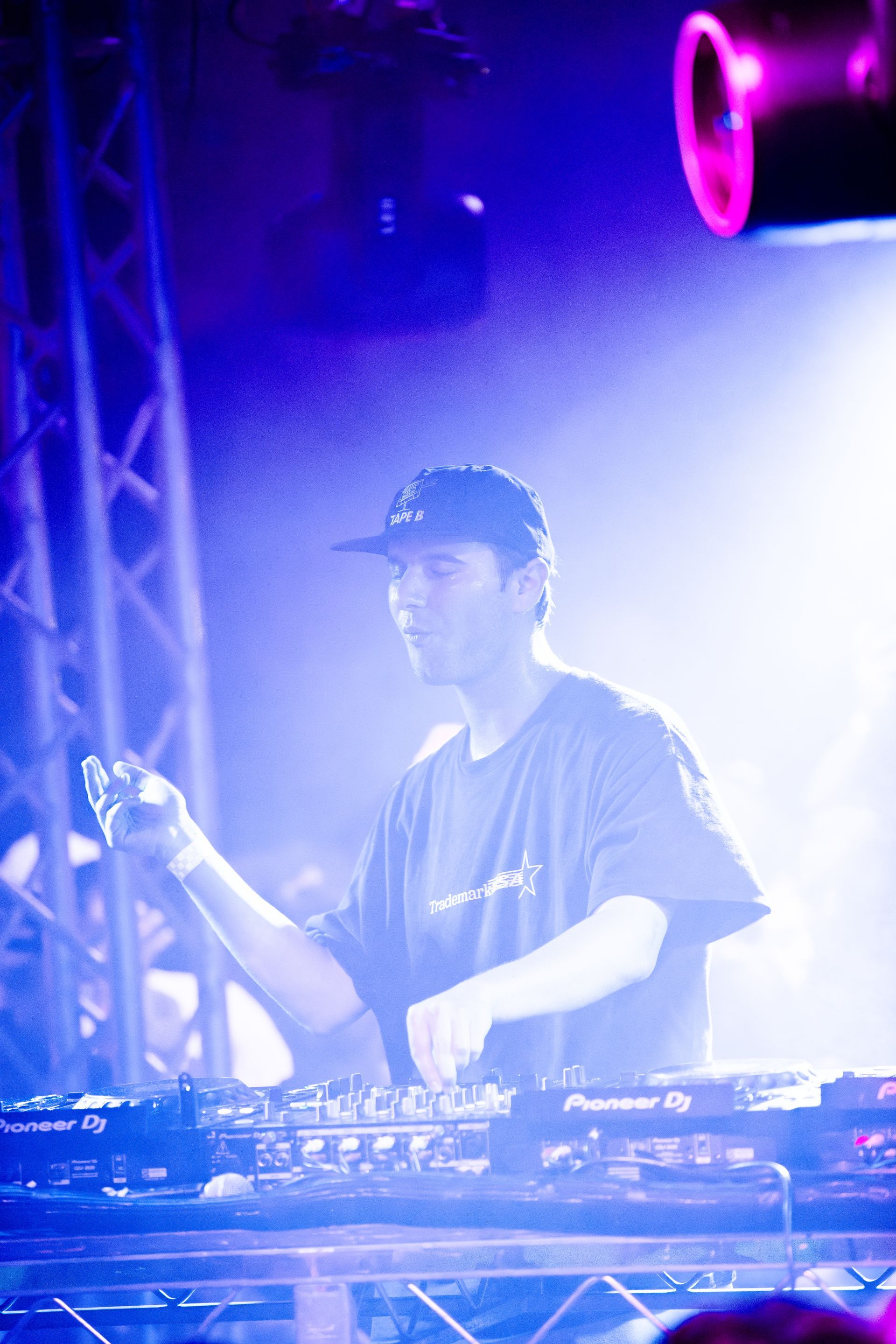 A man is playing a dj set in a dark room.