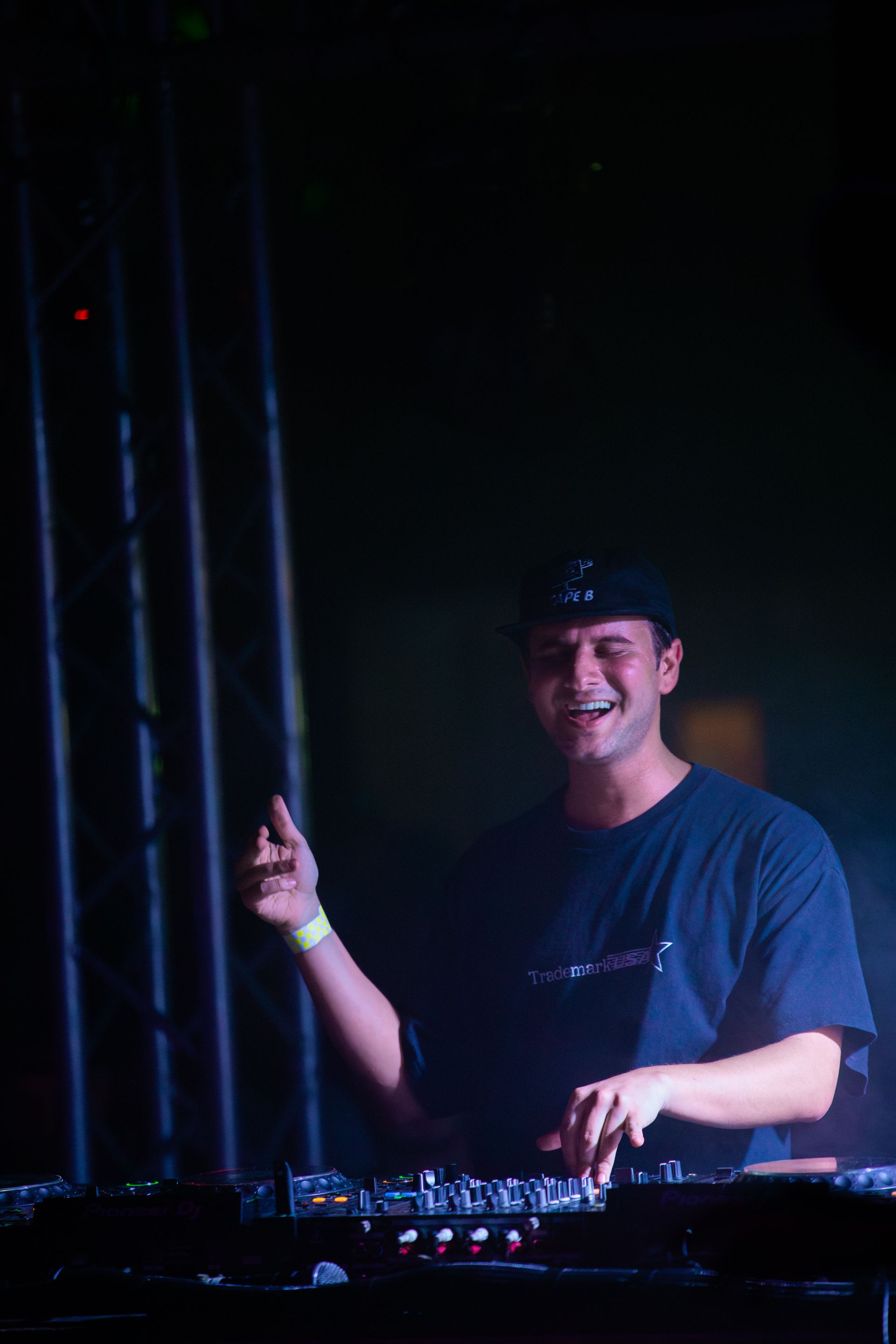 A man is playing a dj set in a dark room.