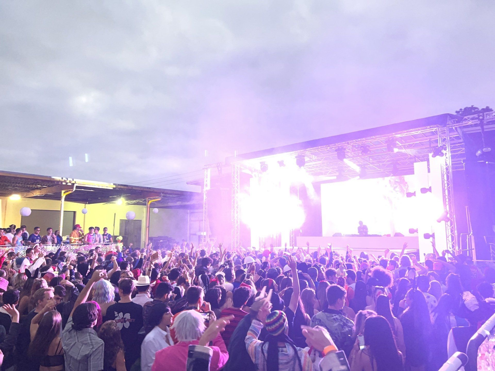 A crowd of people are standing in front of a stage at a concert.