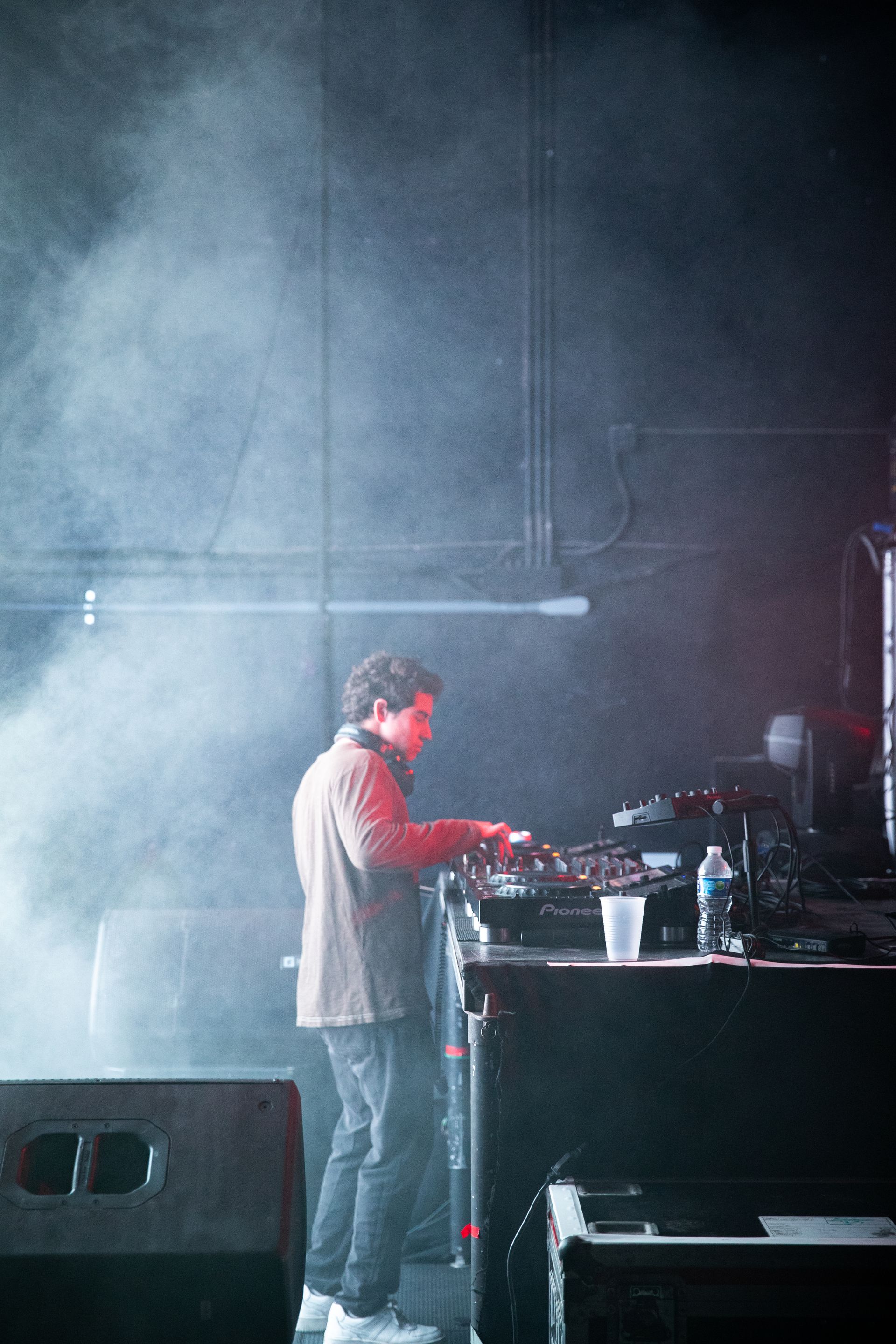 A man is playing a dj set on a stage in a dark room.