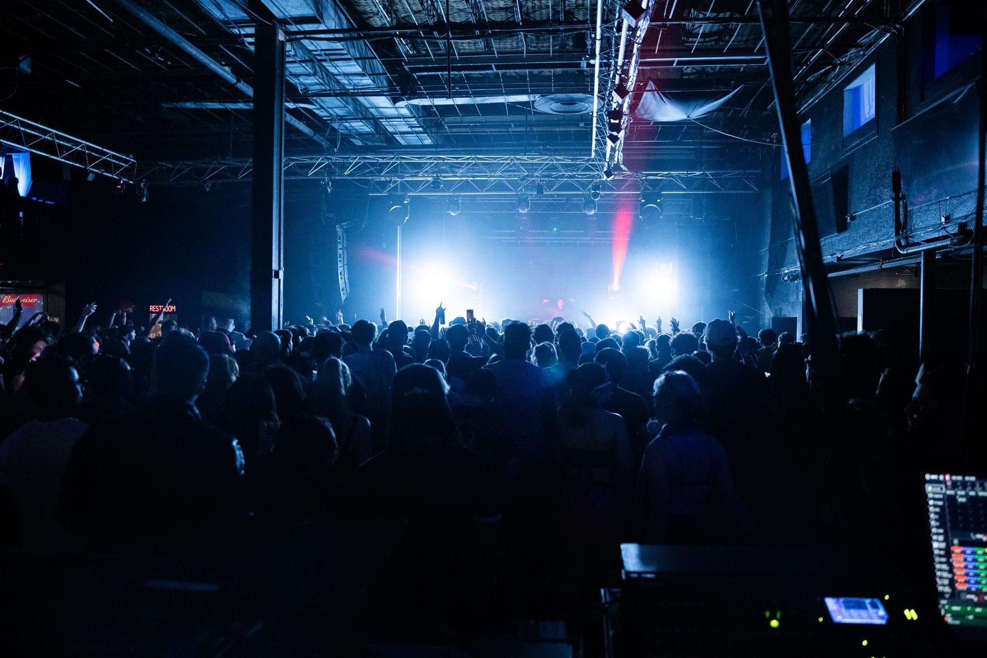 A crowd of people are watching a concert in a dark room.