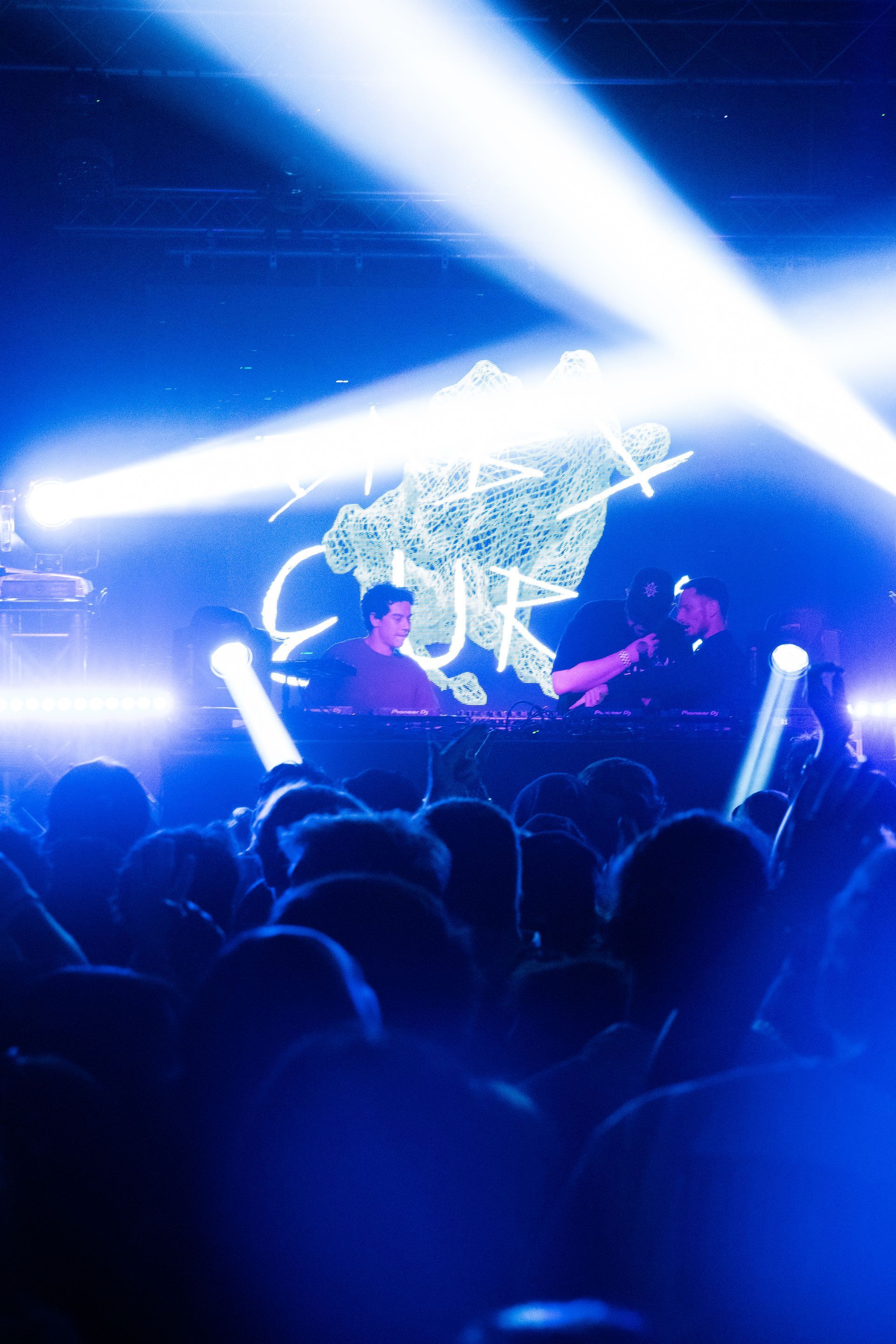 A crowd of people are sitting in front of a stage at a concert.