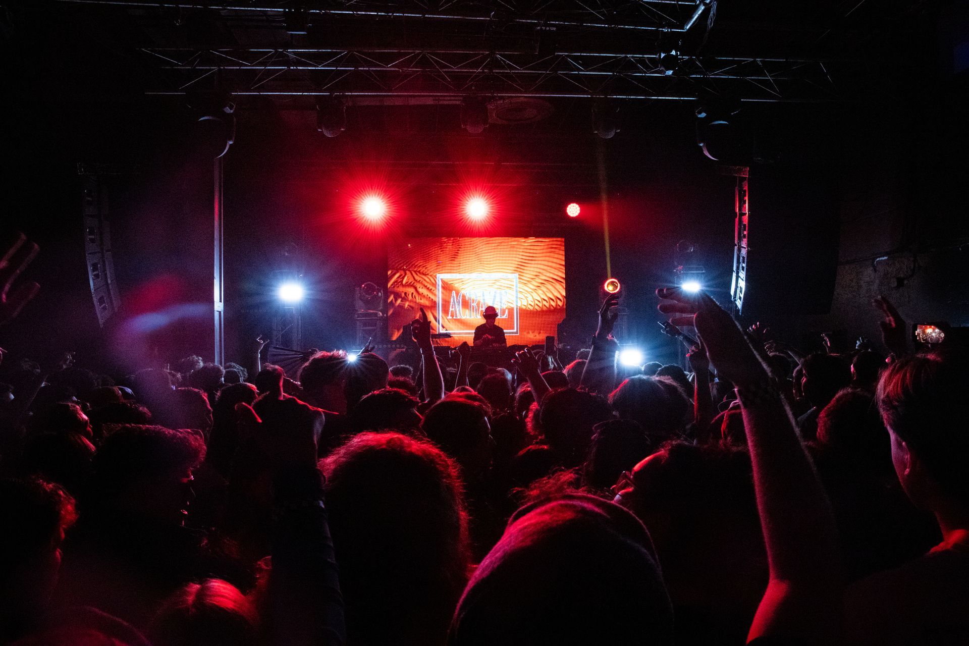 A crowd of people are standing in front of a stage at a concert.
