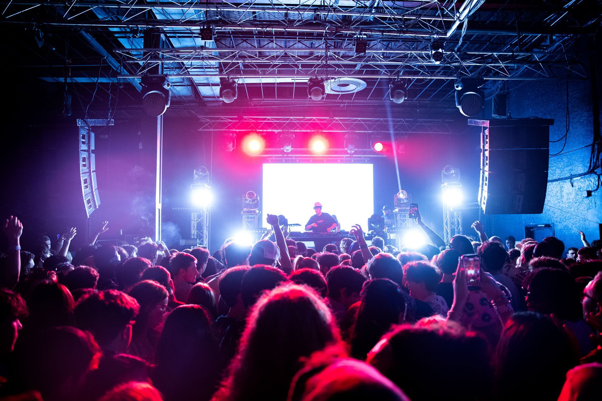 A crowd of people are watching a dj perform on stage