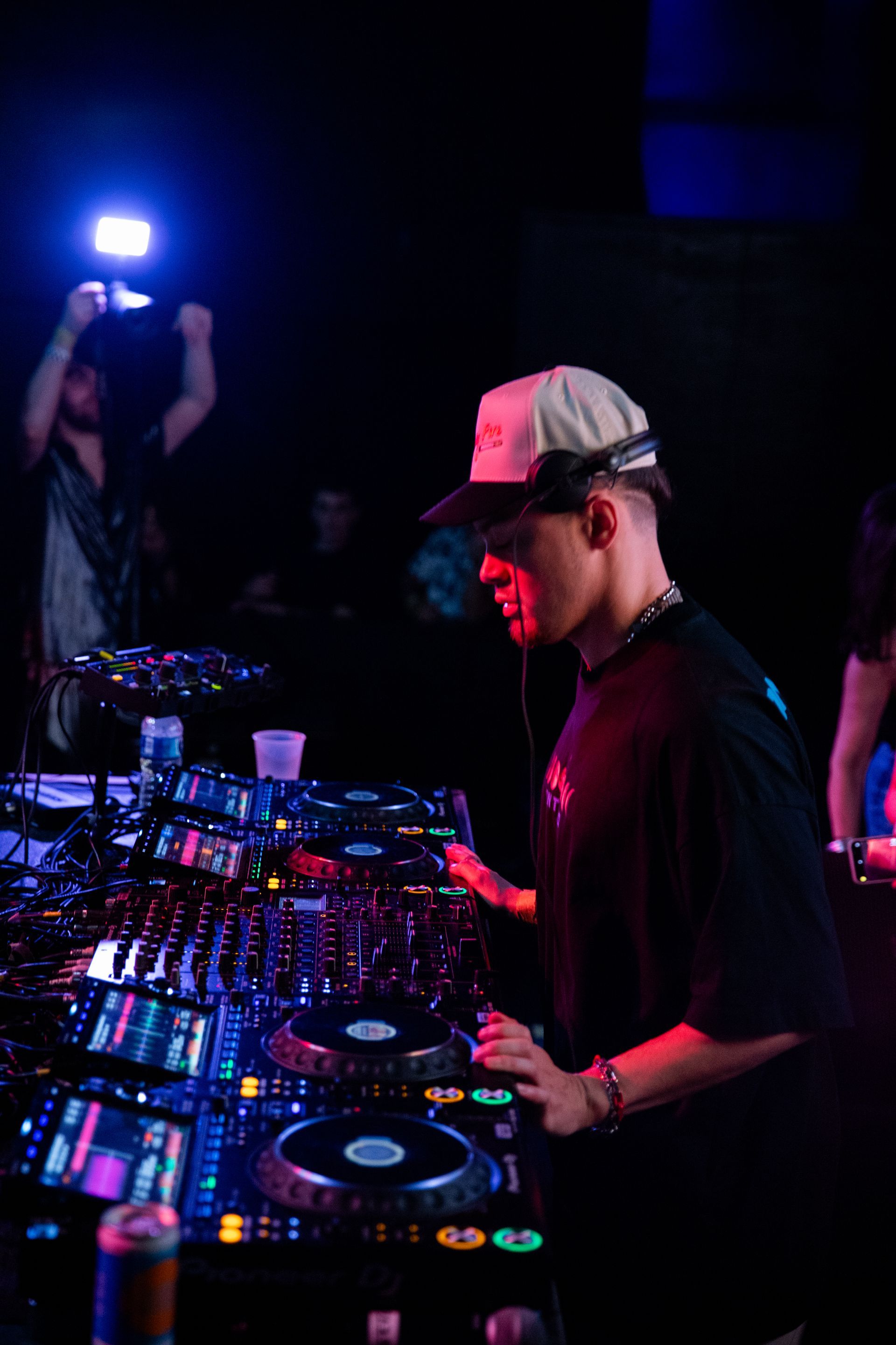 A man is playing a dj set in a dark room.