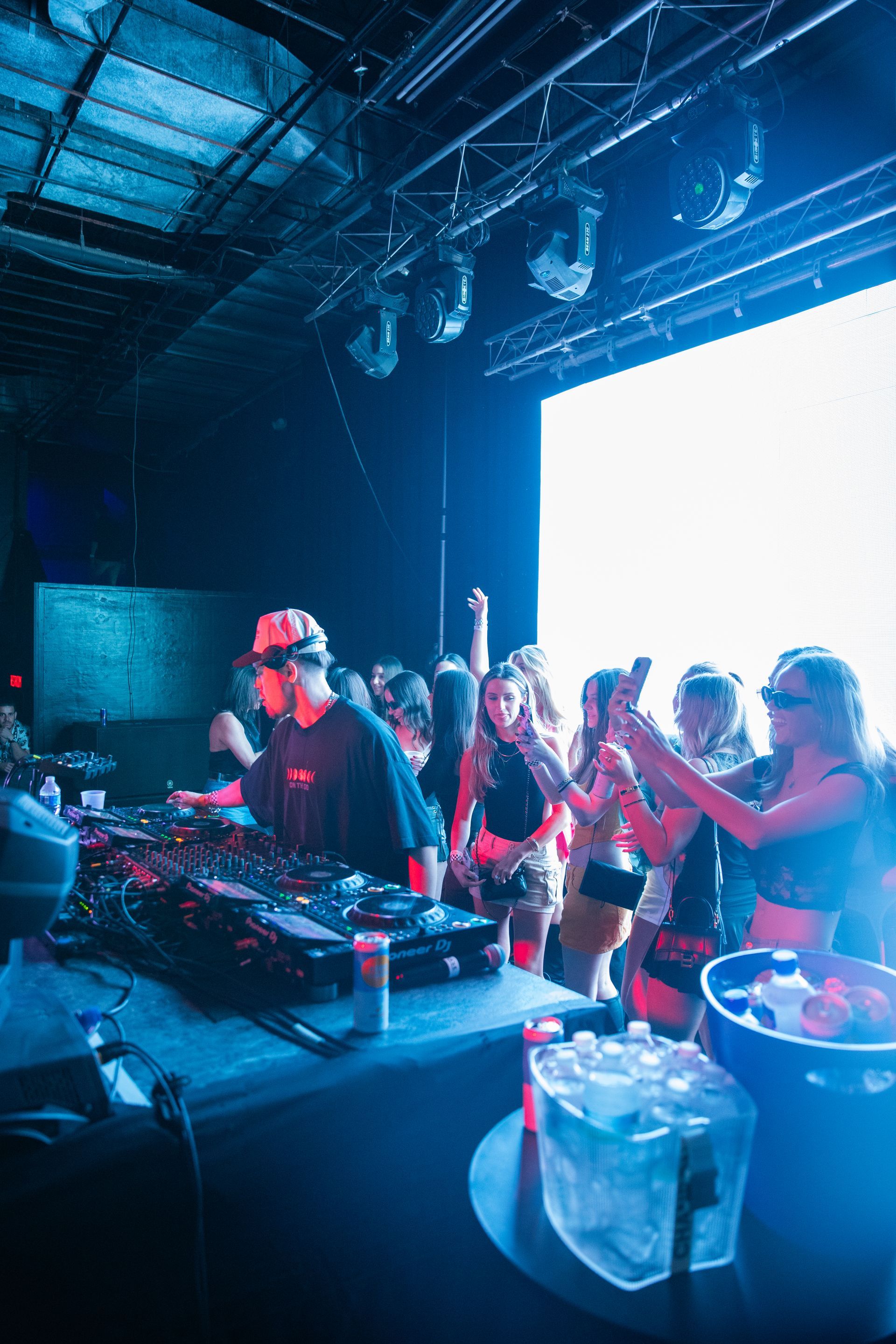 A group of people are dancing in a club while a dj plays music.