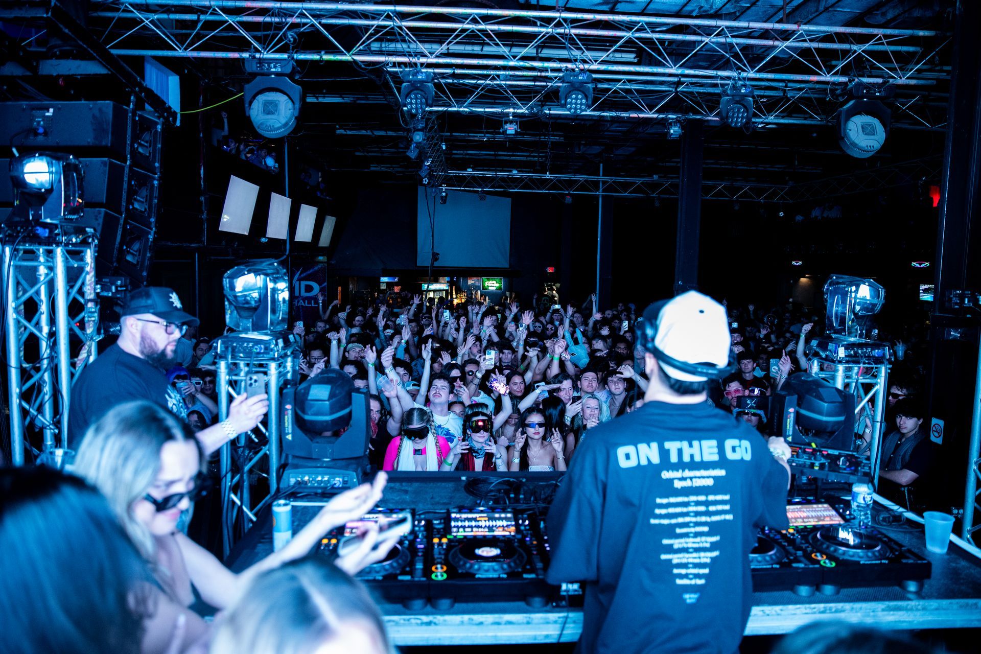 Two dj 's are playing music in front of a crowd and one of them is wearing a shirt that says on the 01