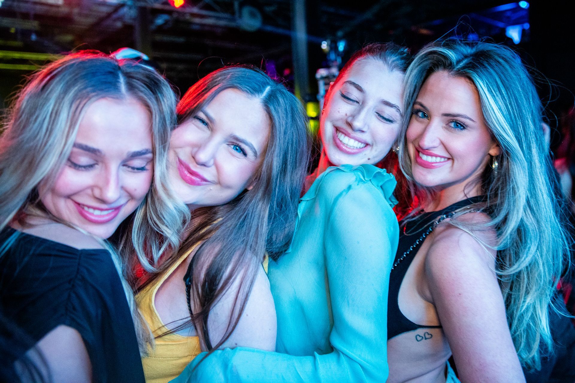 A group of women are posing for a picture together in a club.