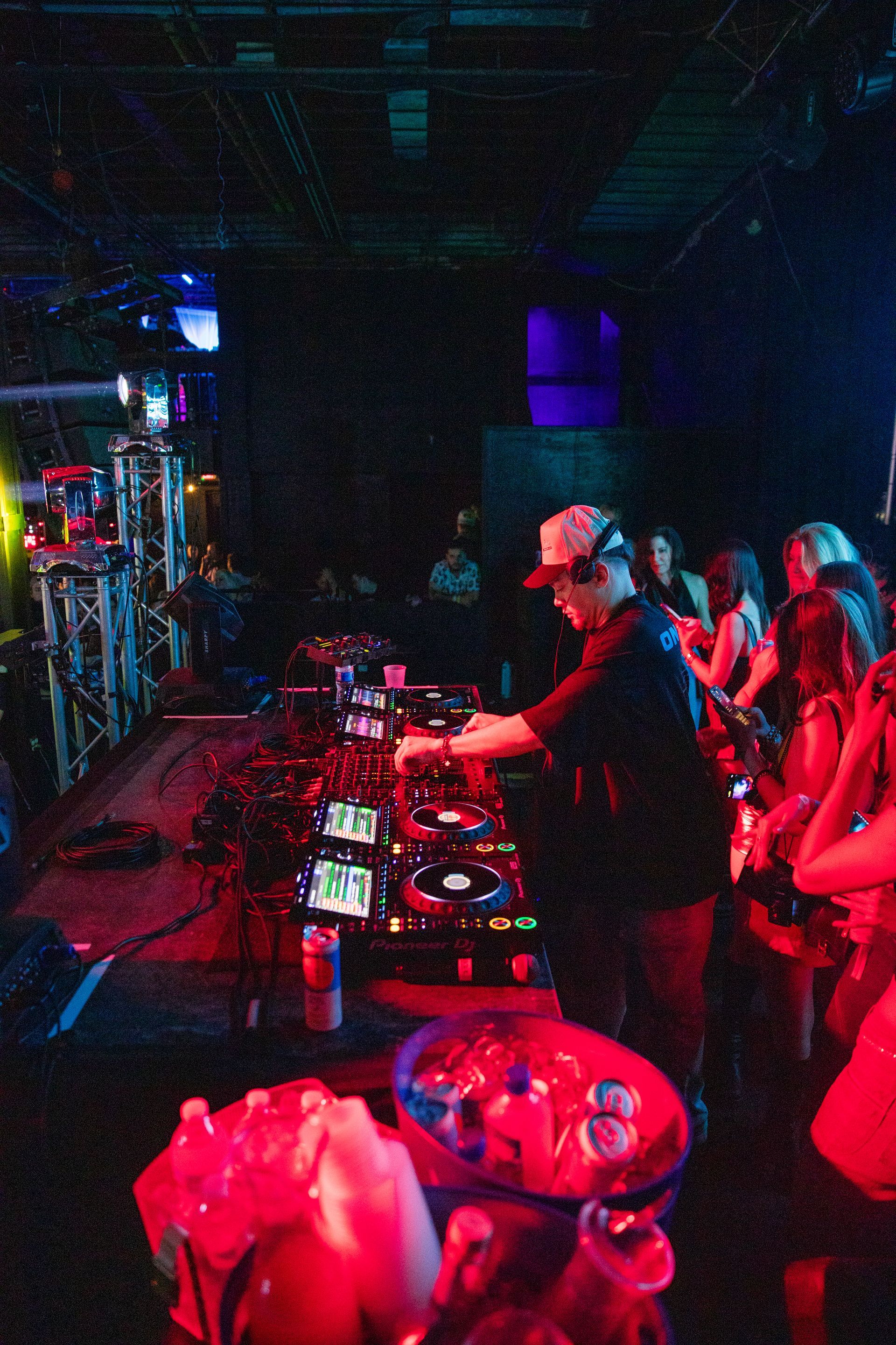 A dj is playing music at a party in a dark room.