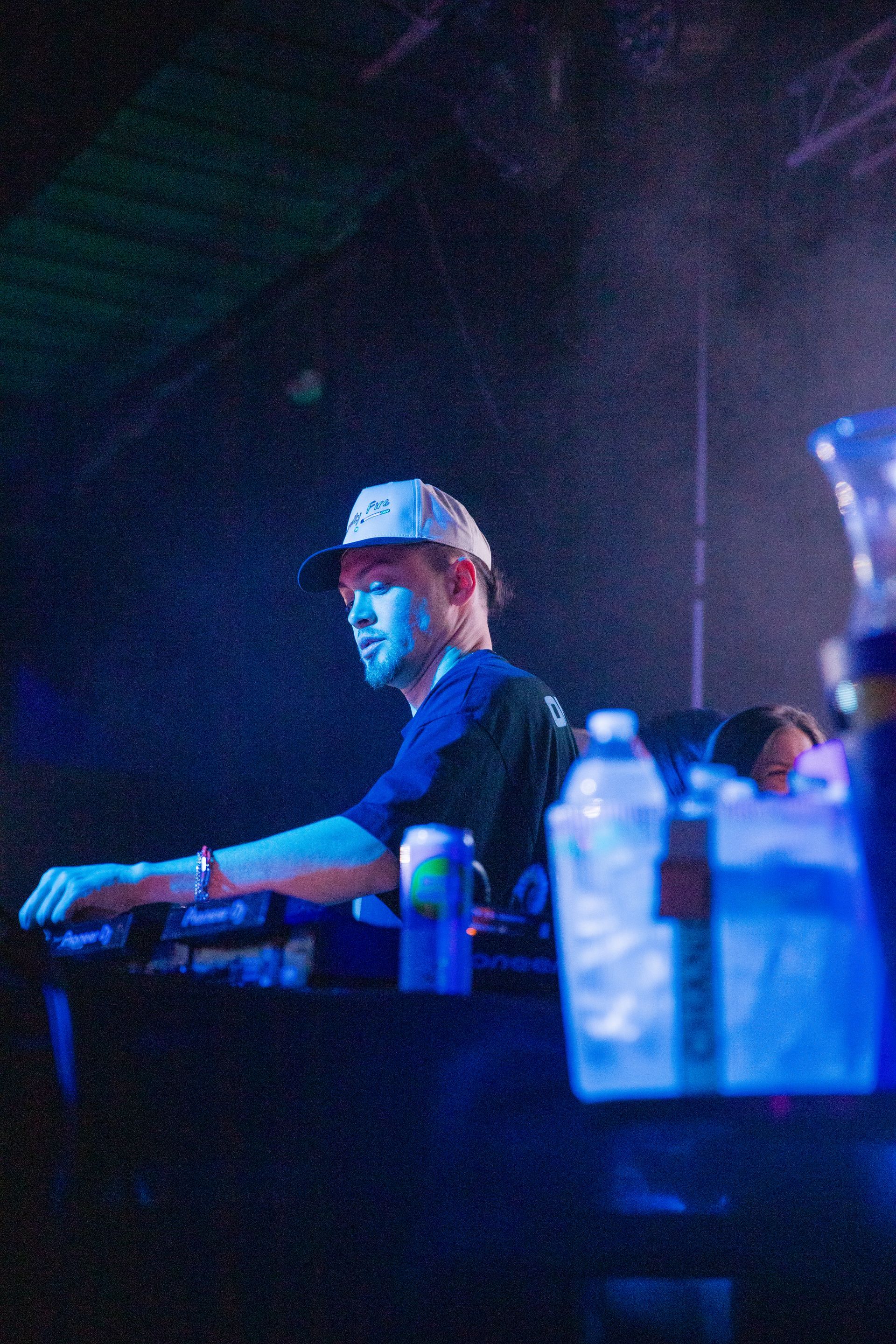 A man in a hat is sitting at a table in a dark room.