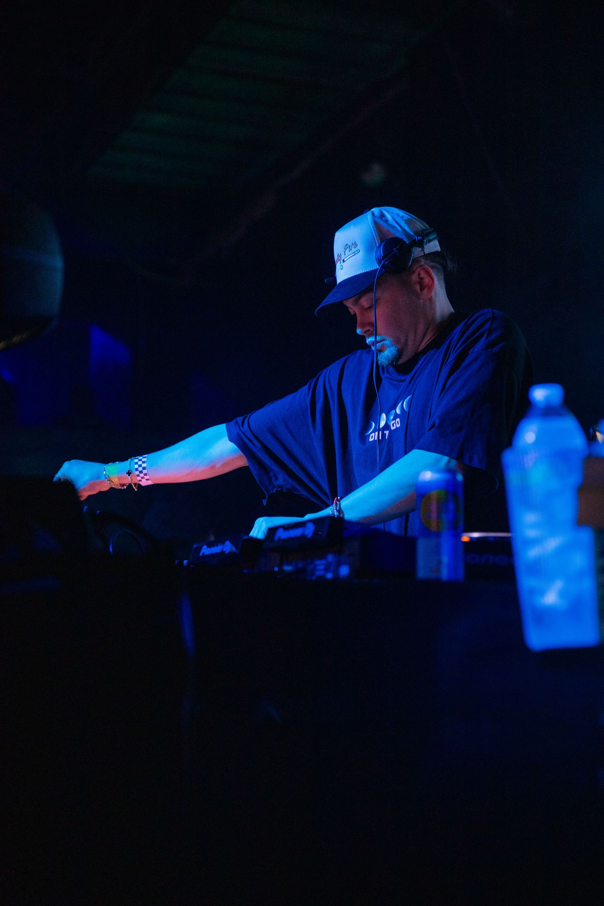 A man in a hat is playing a keyboard in a dark room