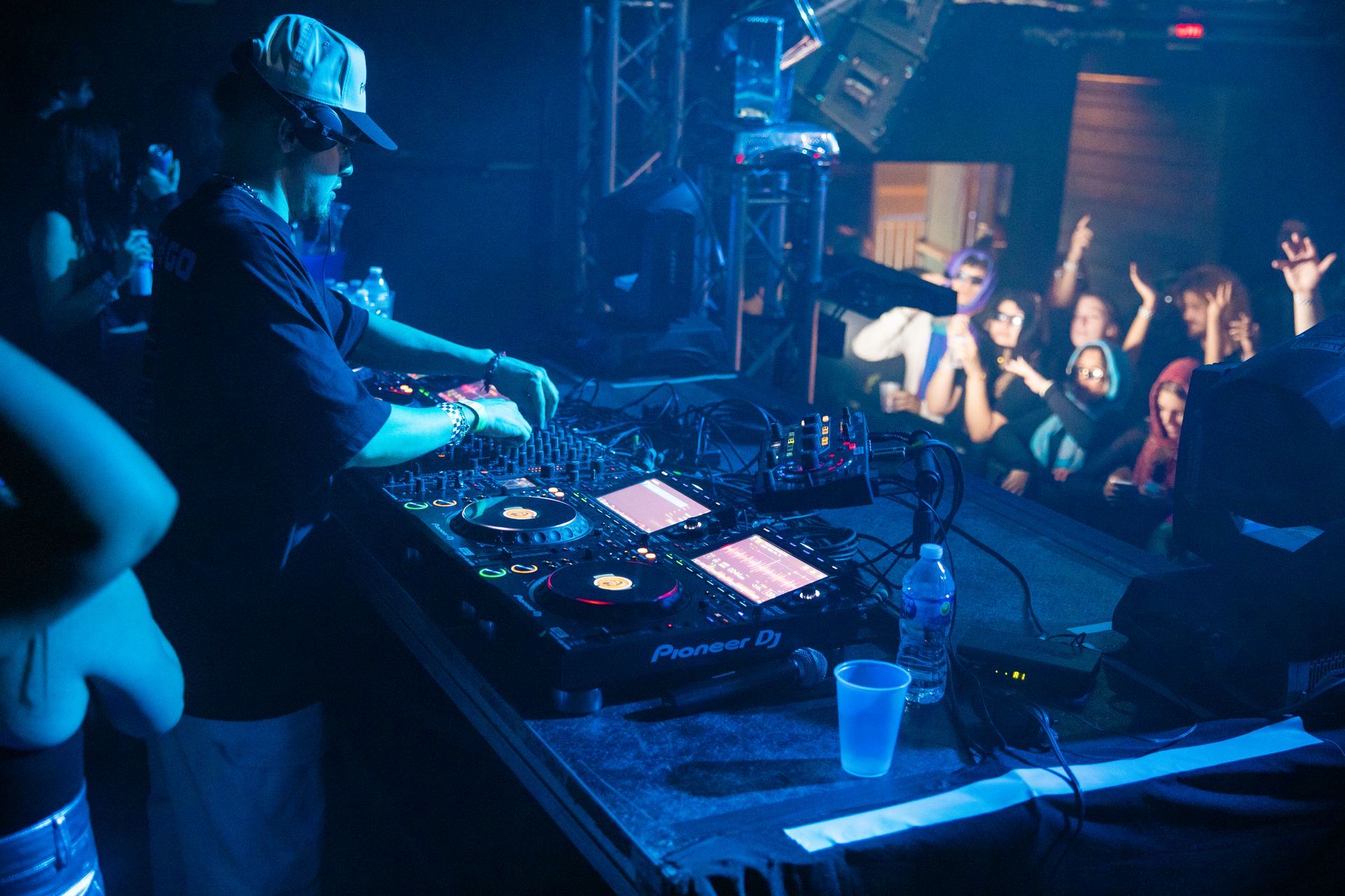 A group of people are watching a dj playing music in front of a crowd.