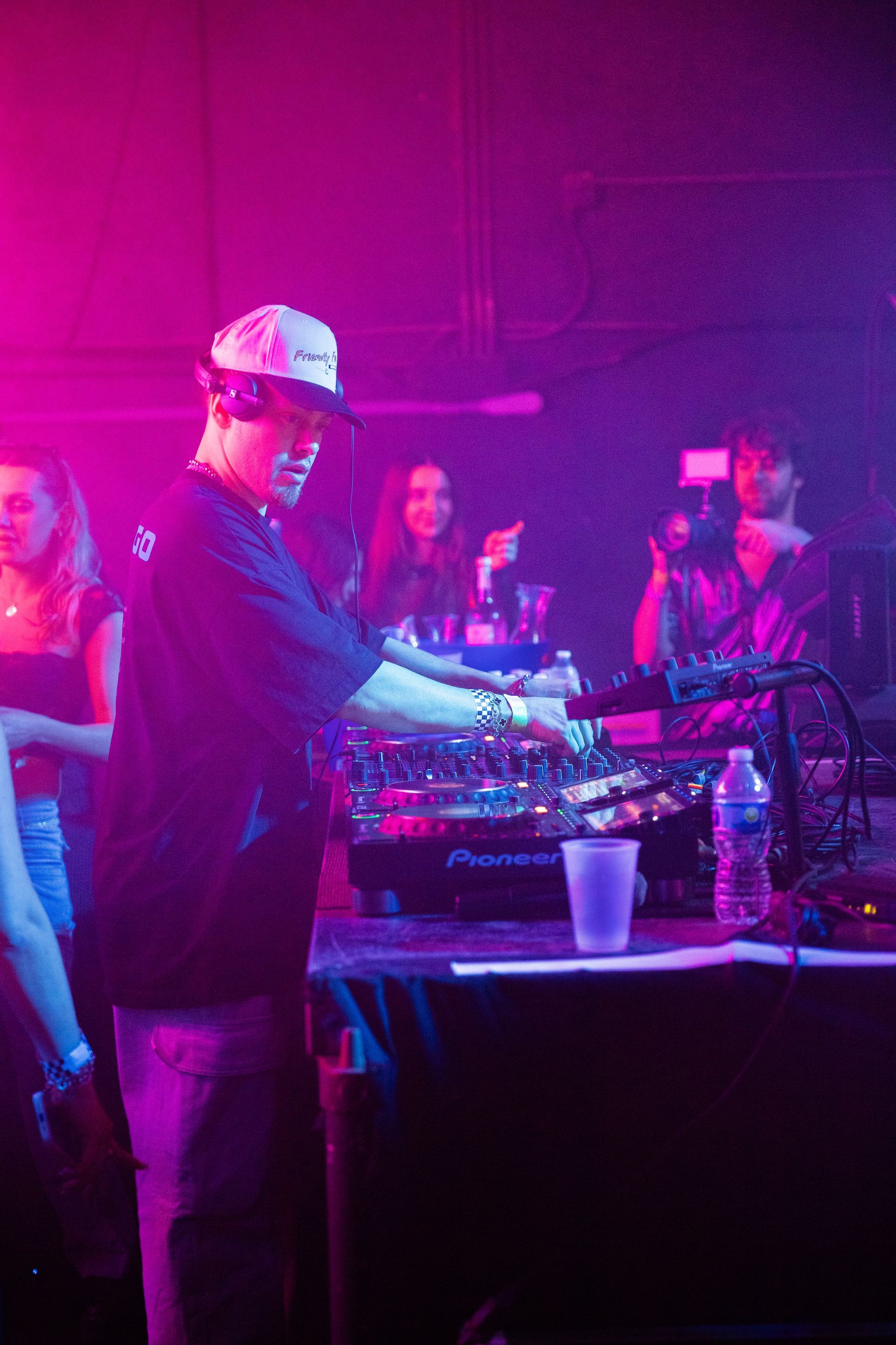 A man is playing a dj set in a dark room with purple lights.
