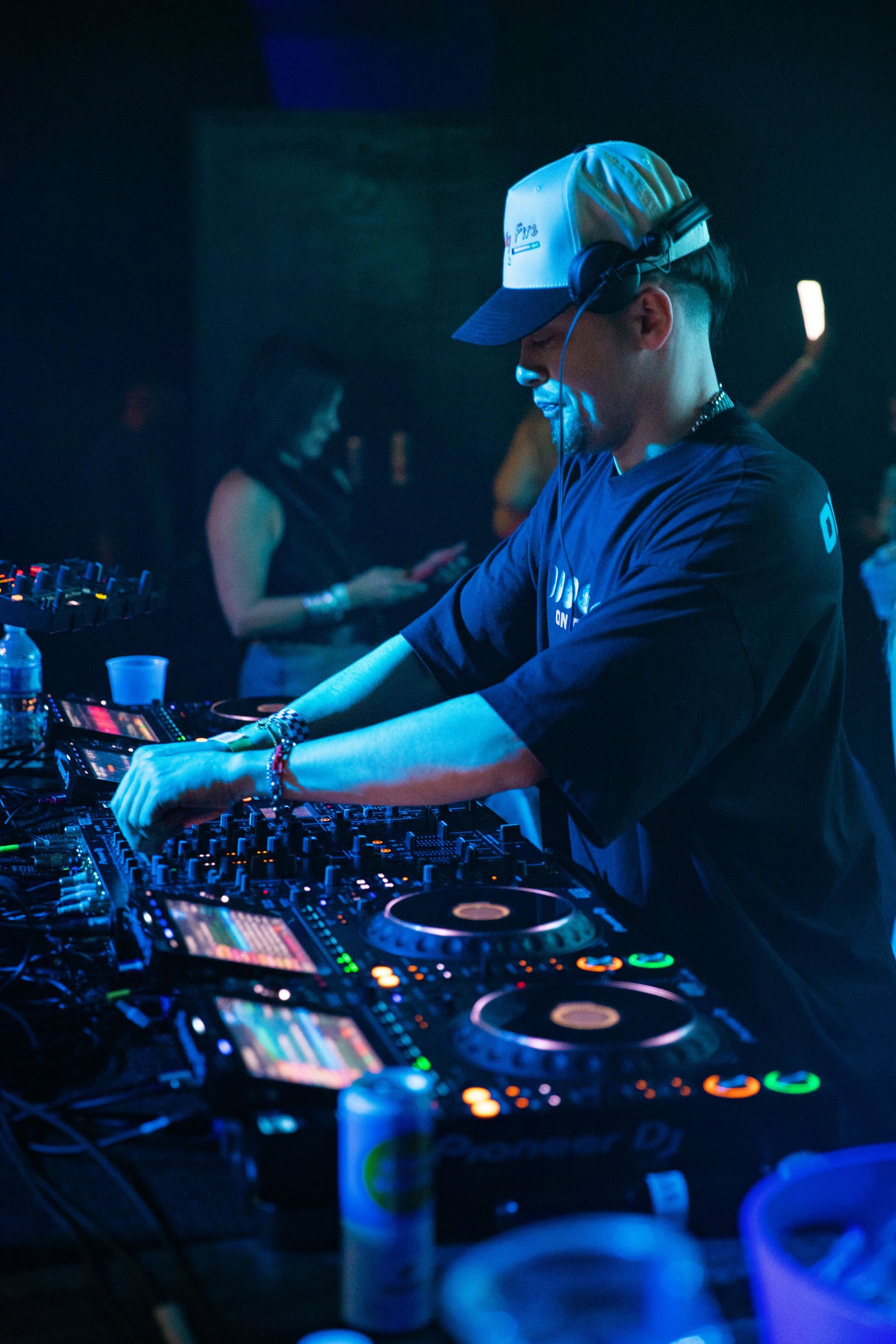 A man wearing a hat is playing music in a dark room.