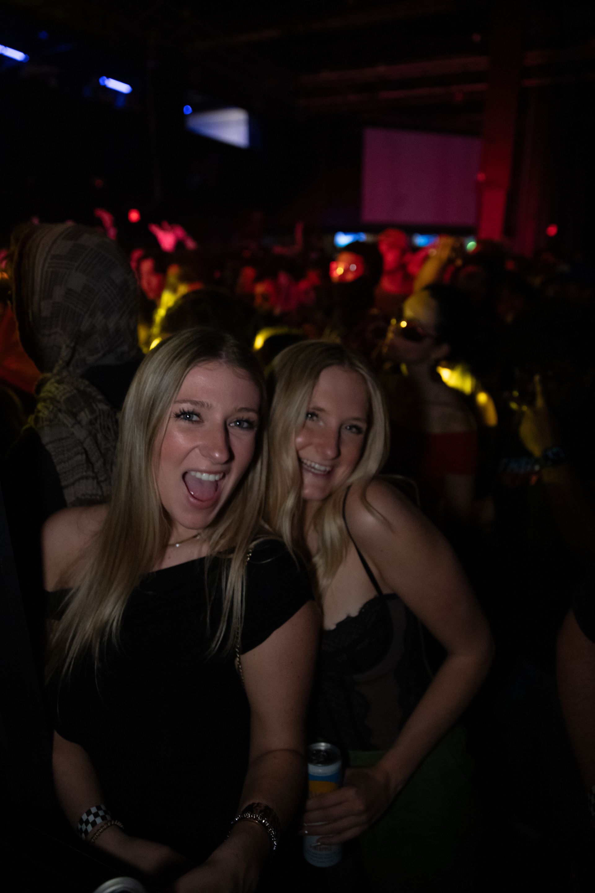 Two women are posing for a picture in a dark room.