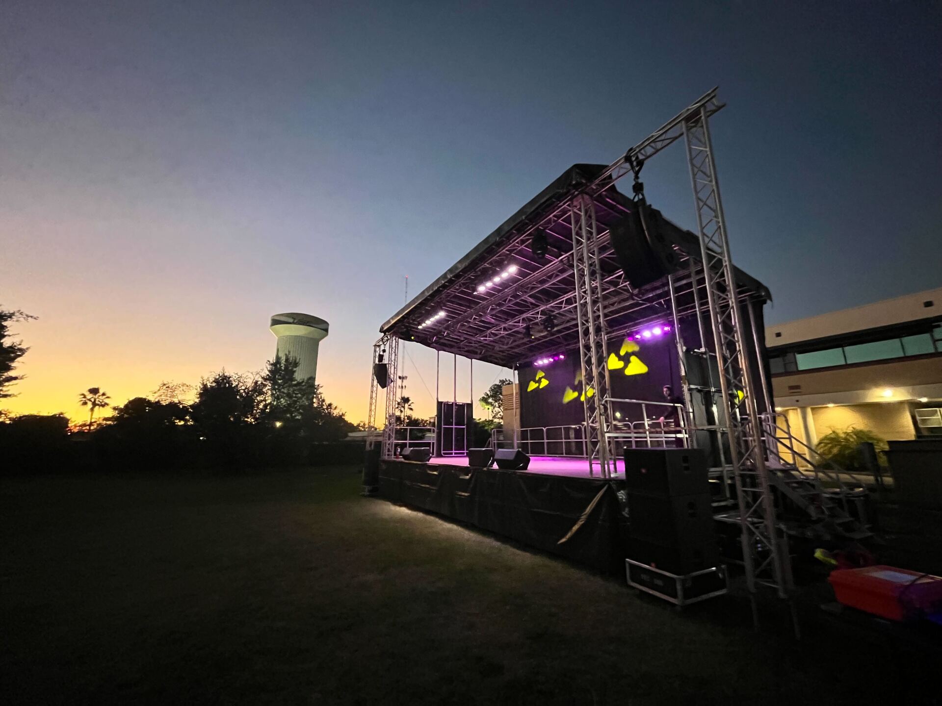 A large stage with a water tower in the background at night.