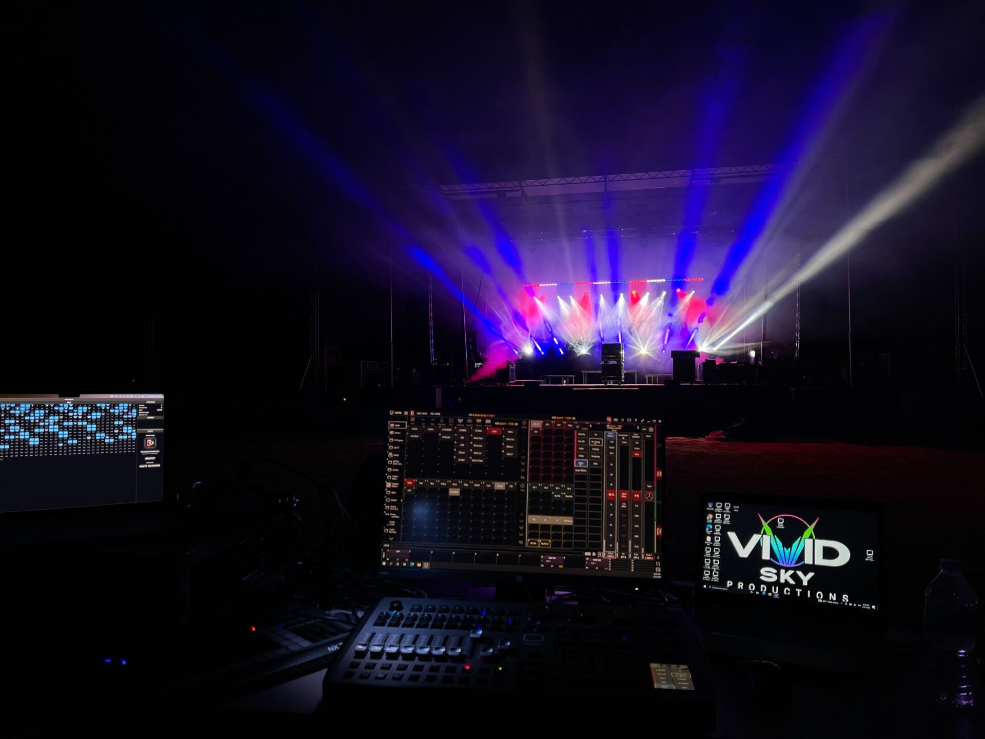 A computer monitor is sitting in front of a stage with a lot of lights coming out of it.