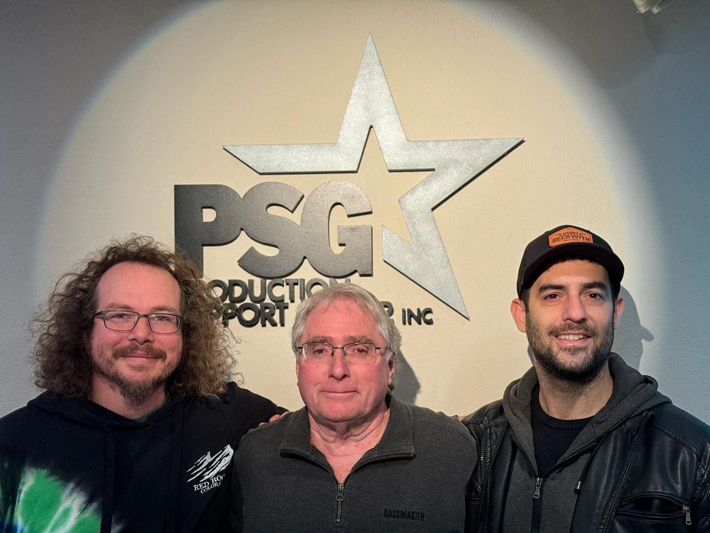 Three men are posing for a picture in front of a psg logo