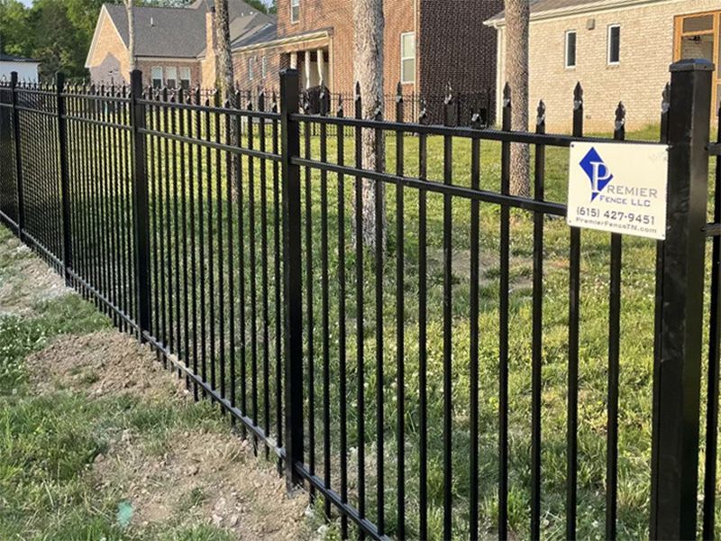Black metal fence in front of a house, with a company sign attached to it.
