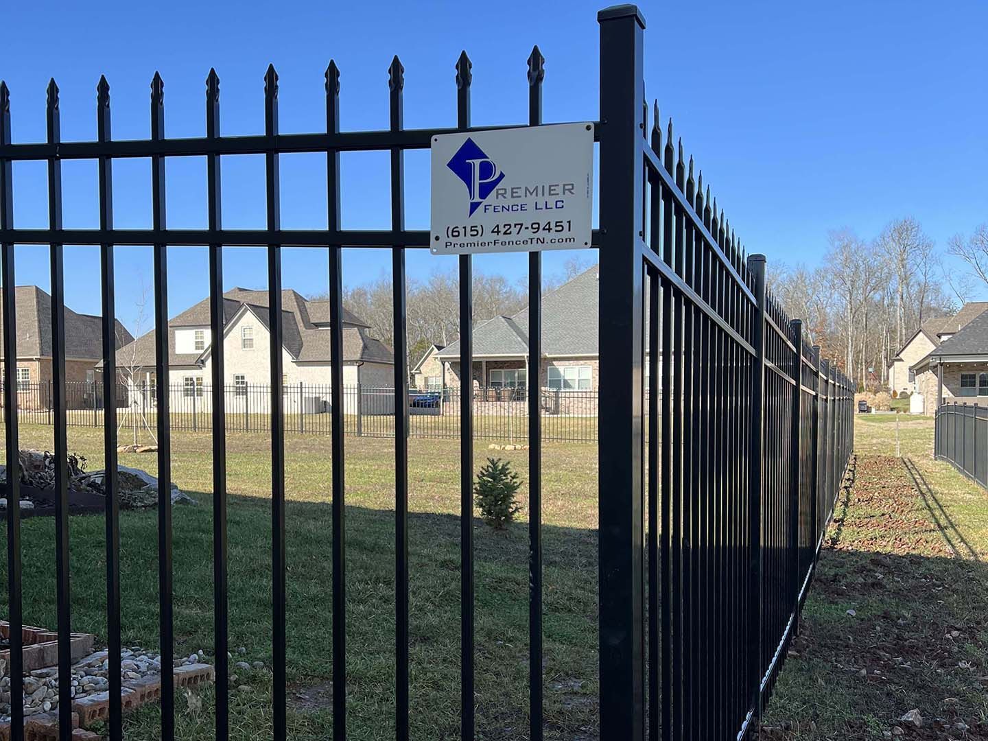 A black wrought iron fence with a sign attached to it.