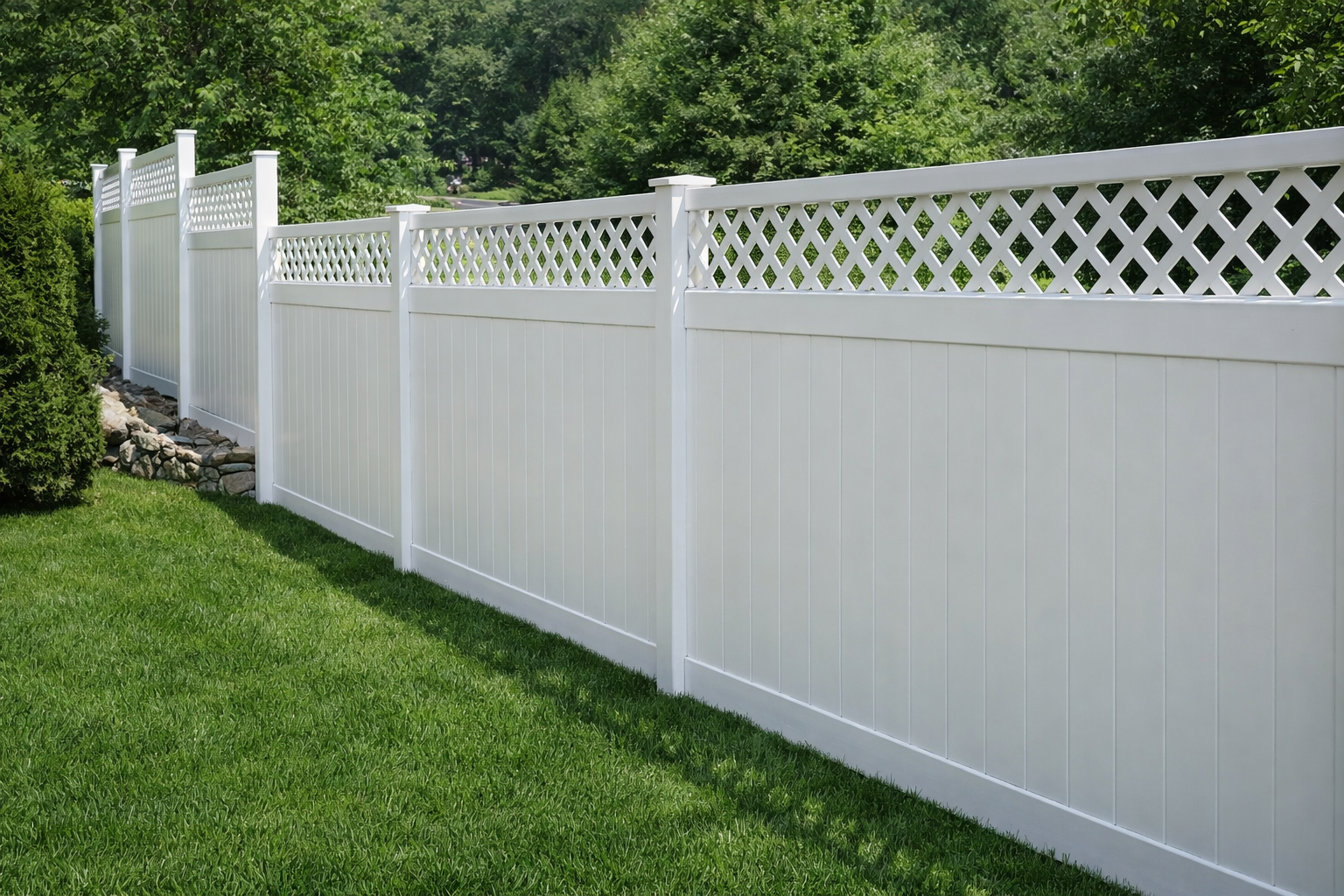 White vinyl fence with lattice top, in a grassy yard, with trees in the background.
