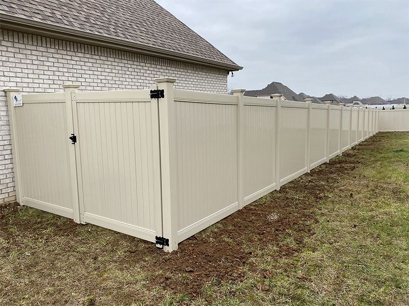 A white fence with a gate is in the backyard of a house.